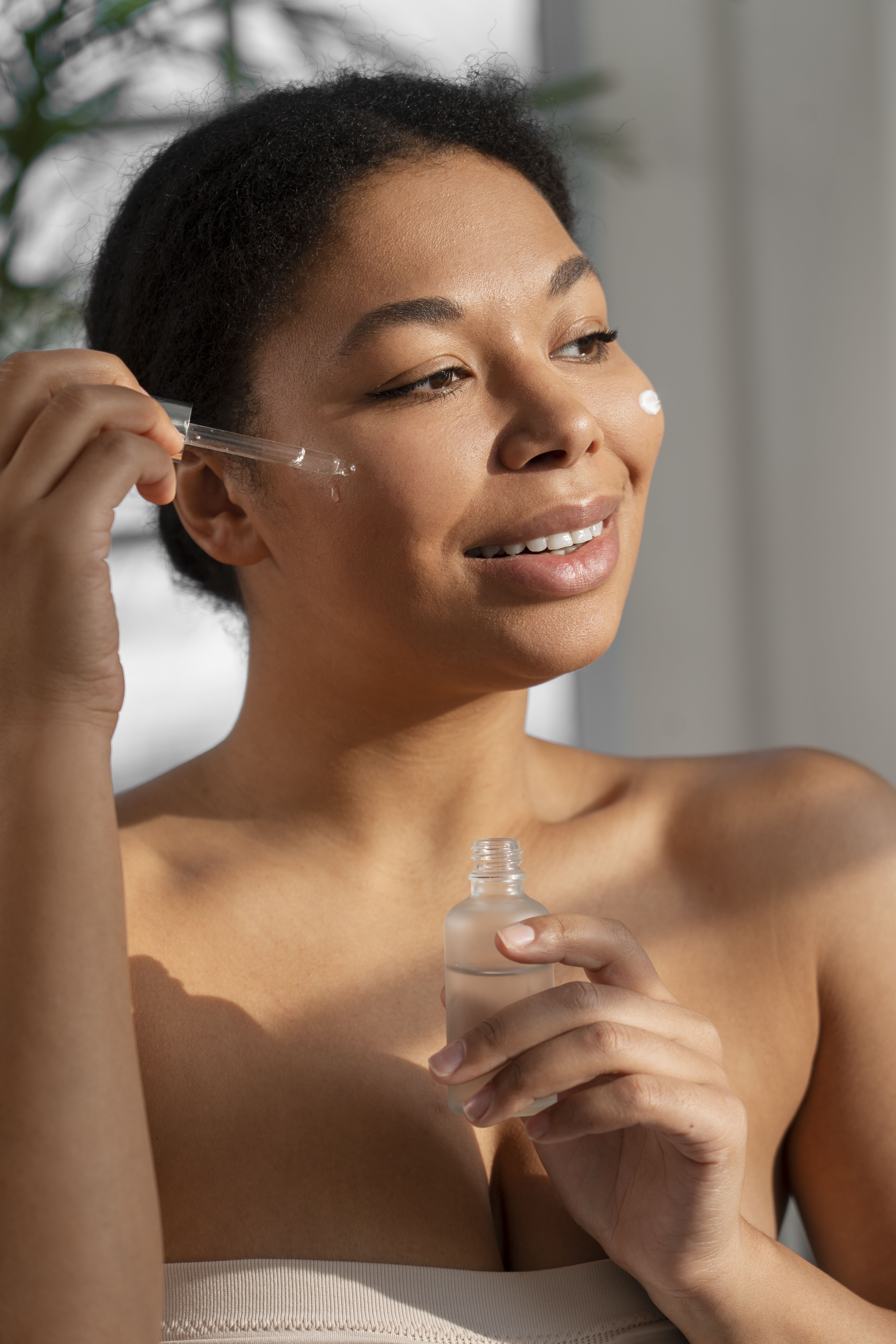 Imagem de mulher aplicando s&eacute;rum de skincare no rosto.