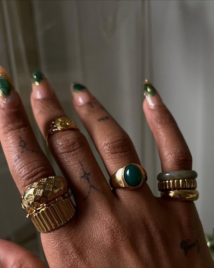 Mix de an&eacute;is dourados e com pedra verde traz toque moderno &agrave;s m&atilde;os