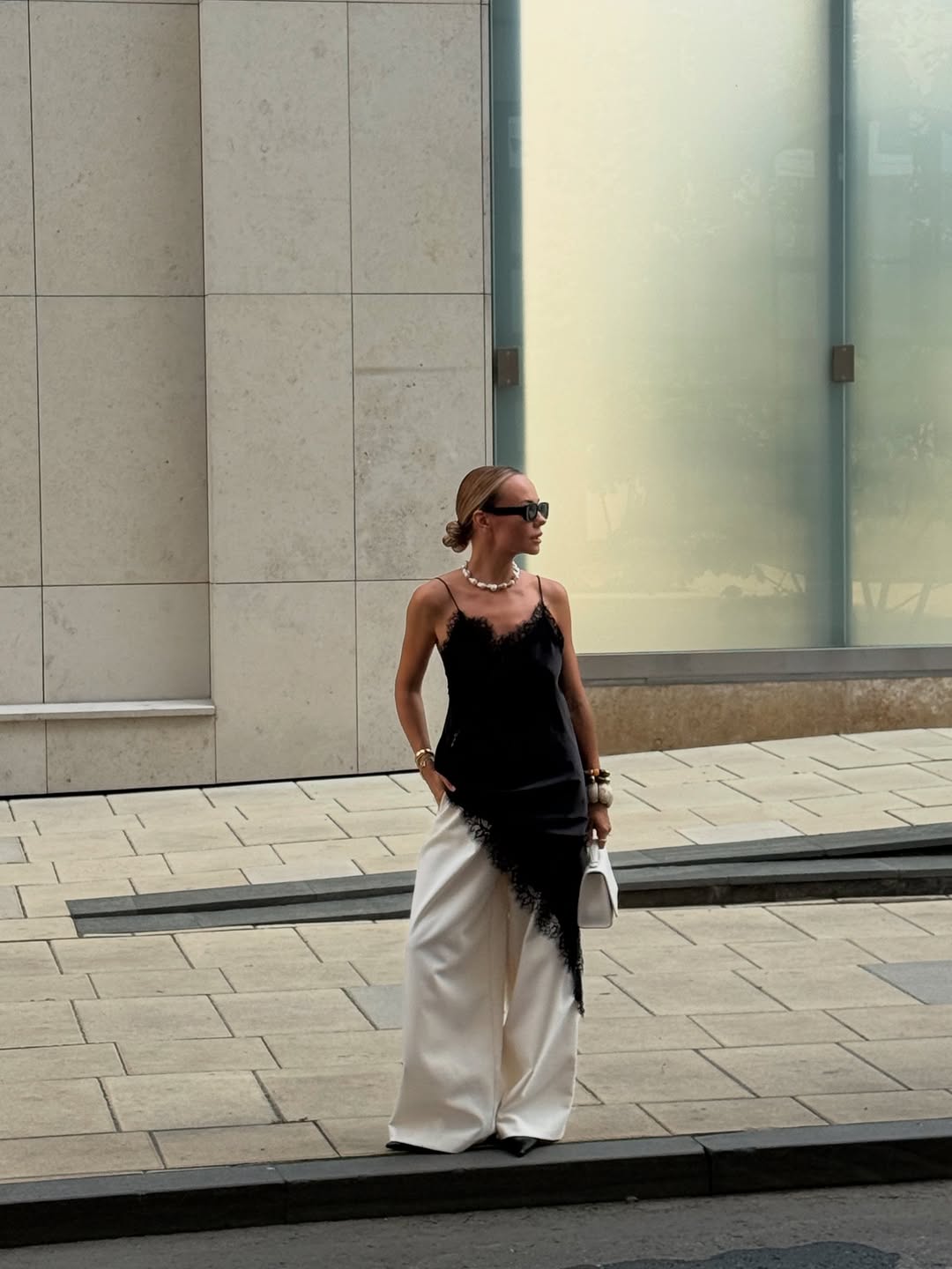 Vestido preto de renda sobre cal&ccedil;a branca ampla em look moderno