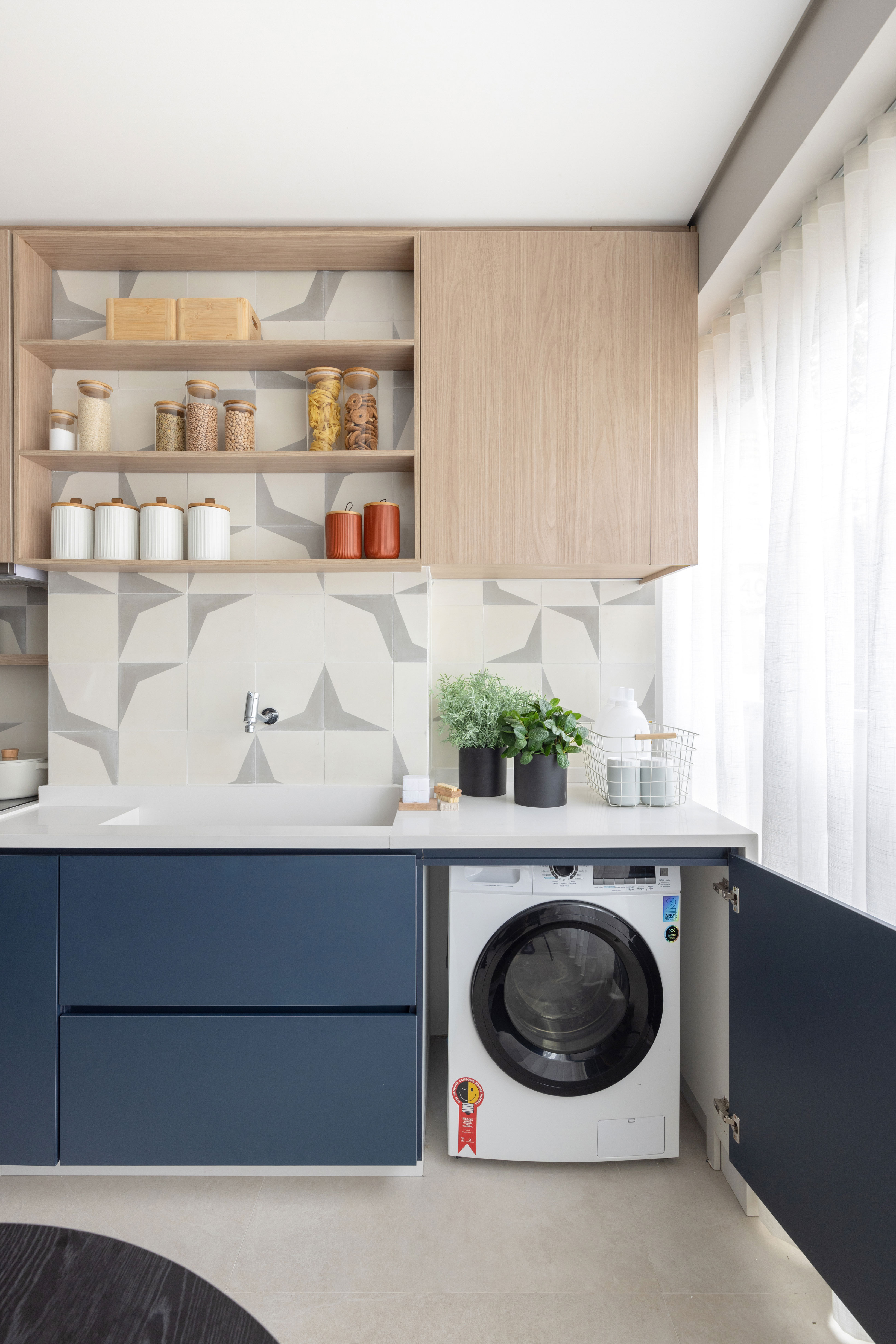 Lavanderia junto de cozinha escondida em arm&aacute;rio de marcenaria azul.