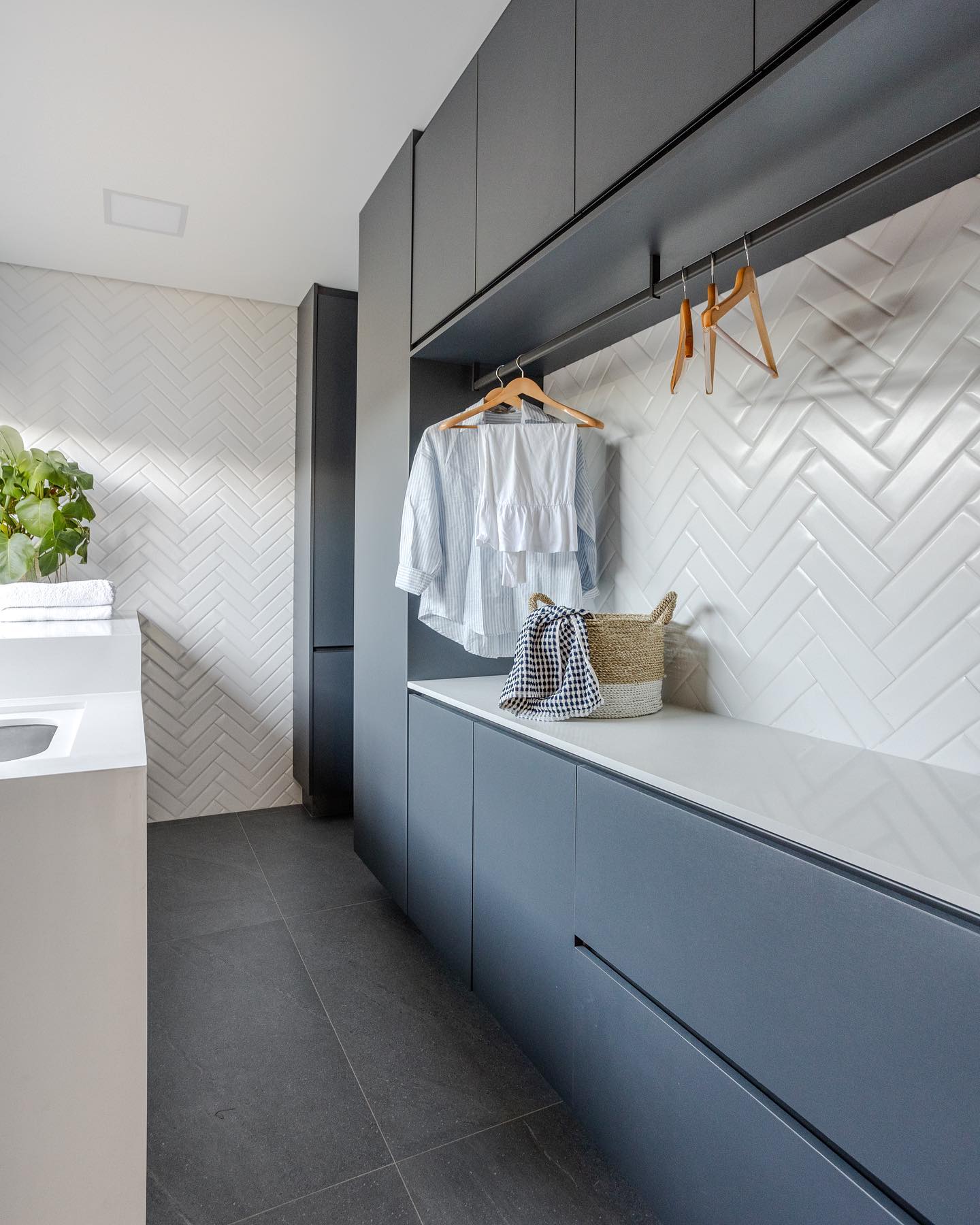 Lavanderia com parede de ladrilhos branca e MDF em azul e cinza escuro.