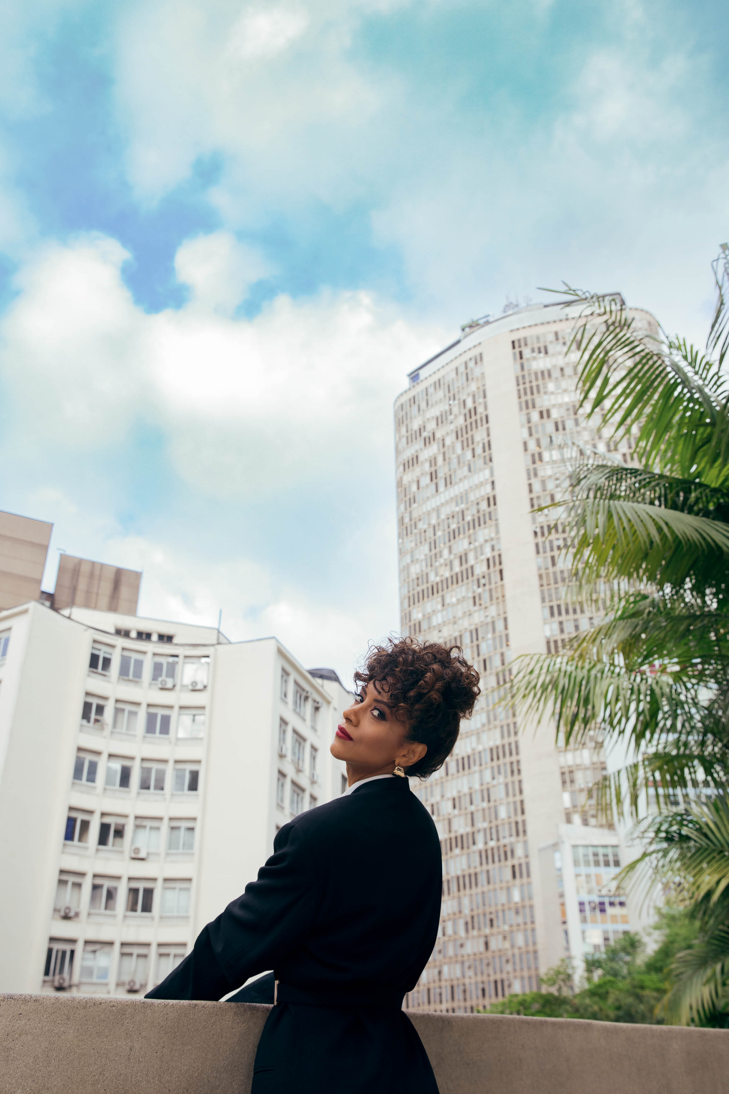 Mulher apoiada em parapeito de pr&eacute;dio olhando para tr&aacute;s