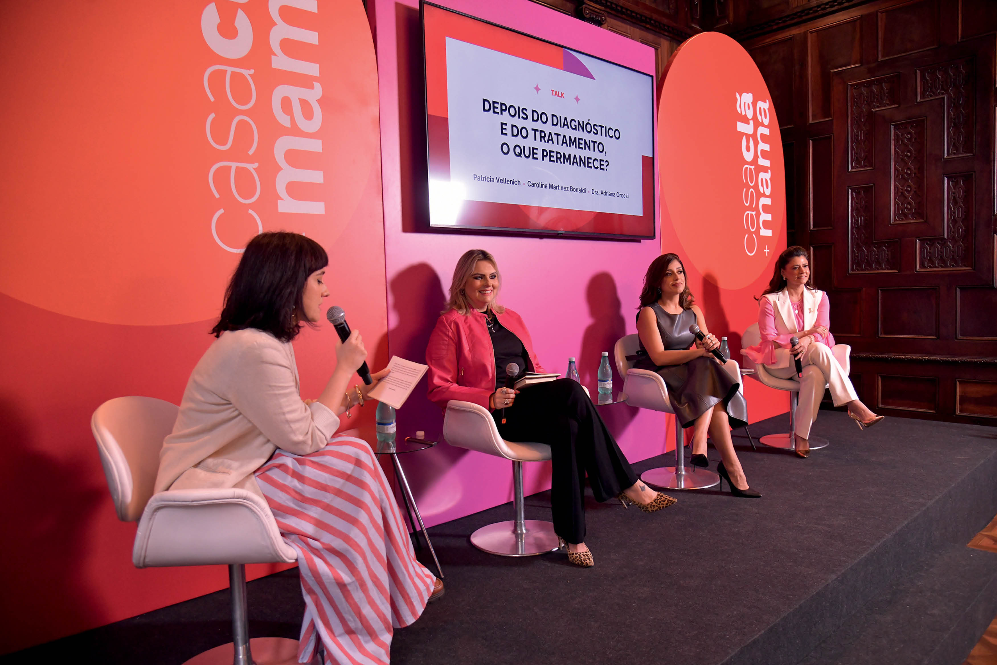 Palco de palestra com quatro mulheres sentadas palestrando.