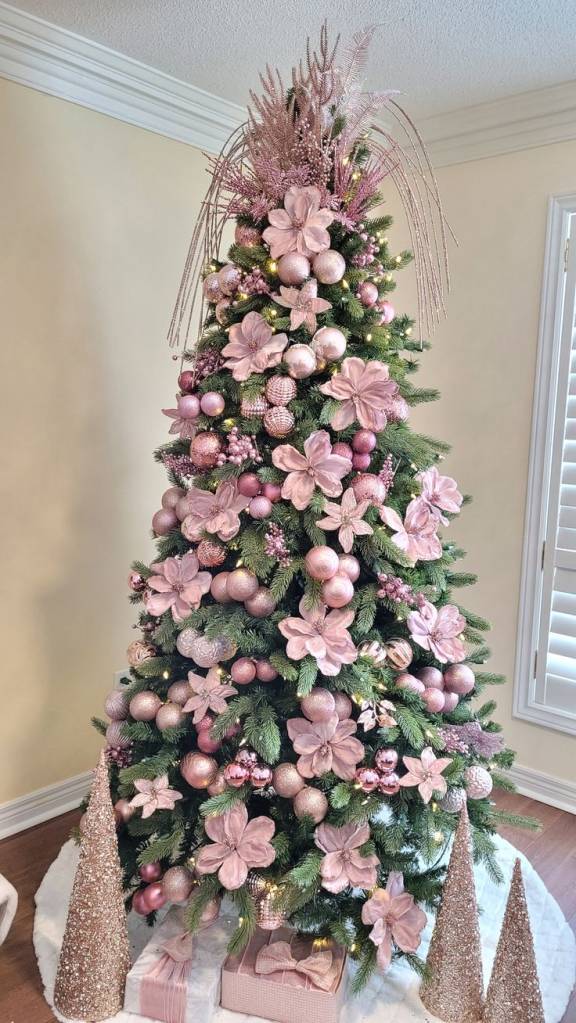 &Aacute;rvore de Natal verde decorada com flores rosas grandes, bolas ros&ecirc; e detalhes delicados em glitter