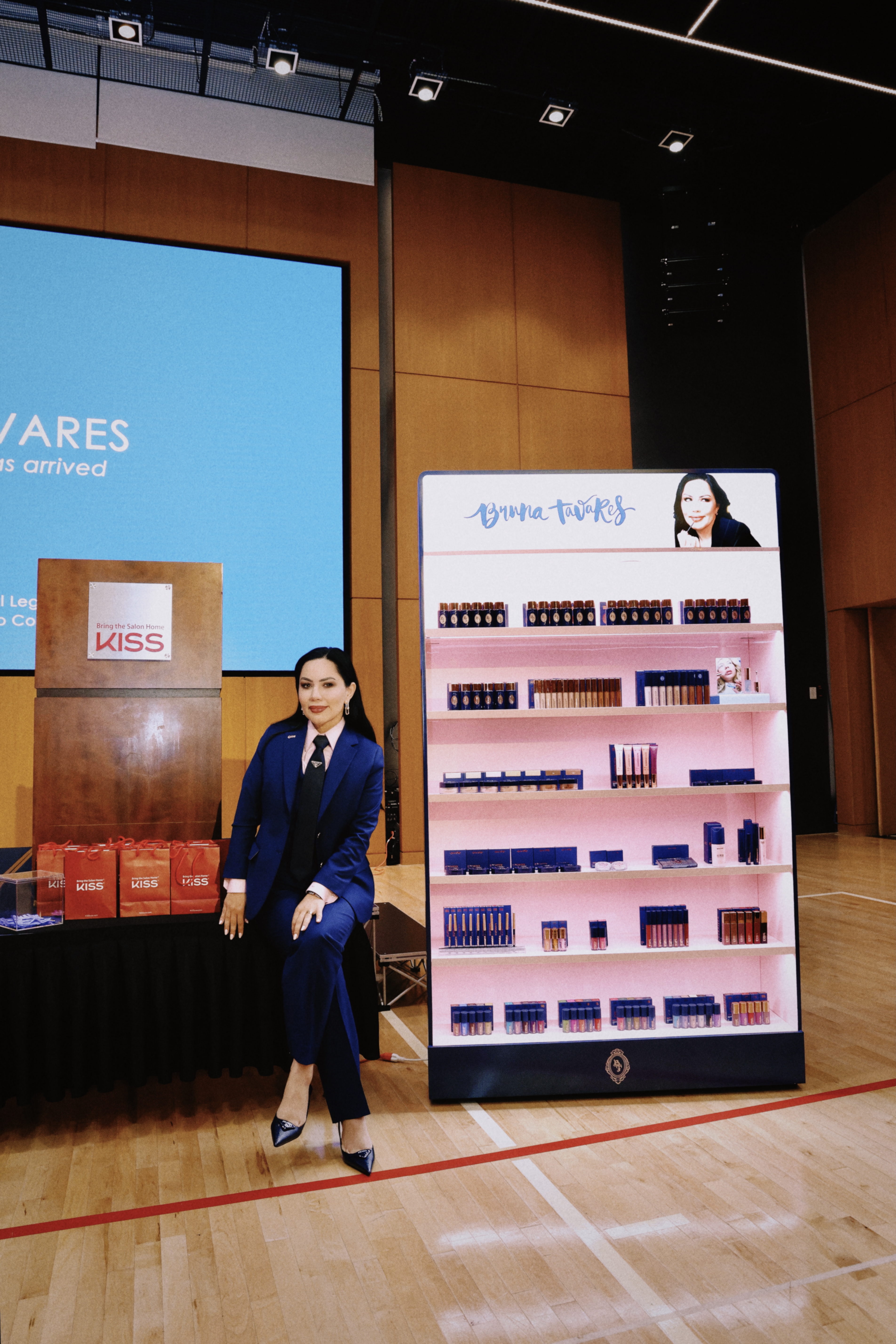 Imagem da empres&aacute;ria Bruna Tavares ao lado de stand da marca BT.