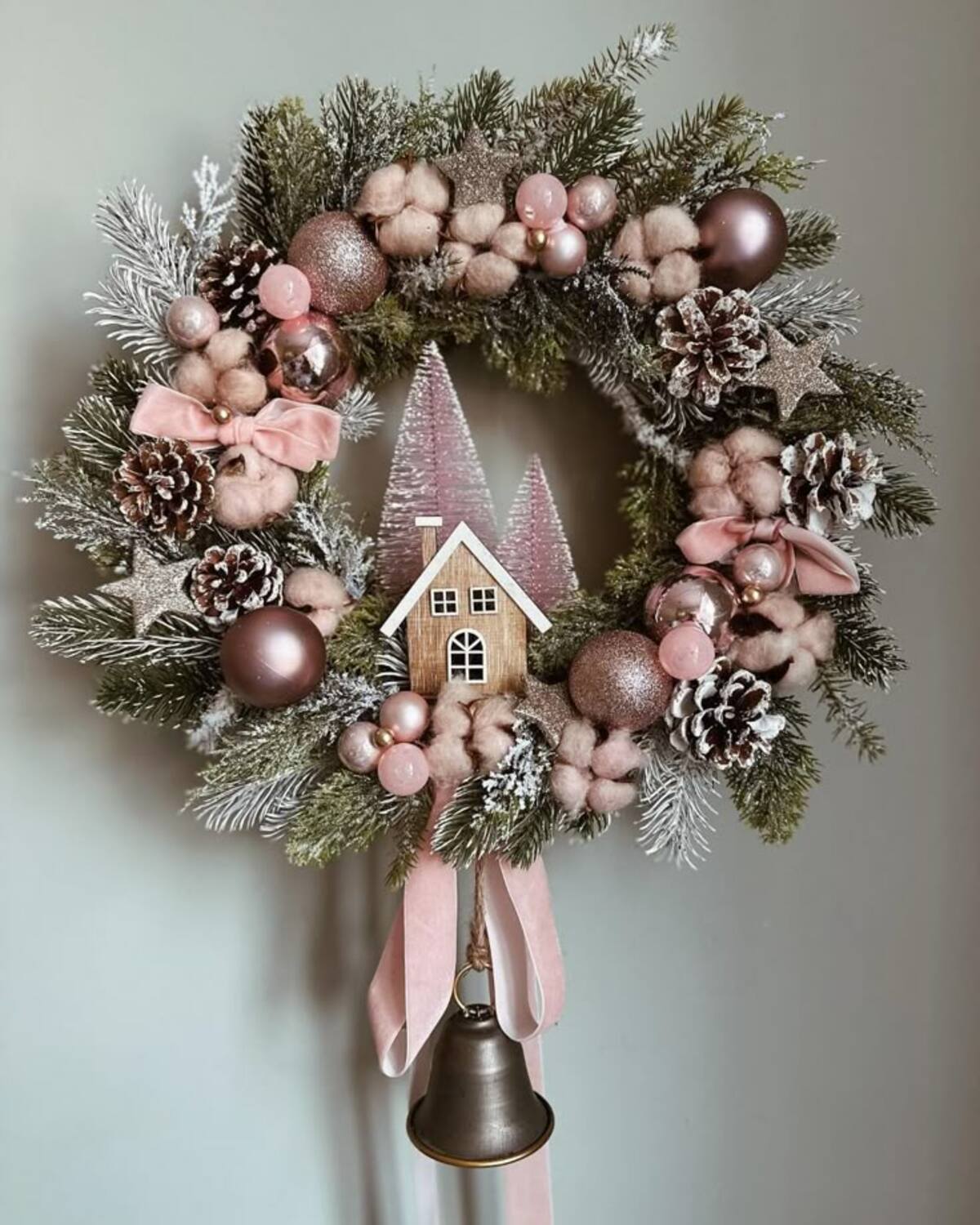 Imagem de guirlanda rosa e verde com bolas de natal, casa e pinheiros.