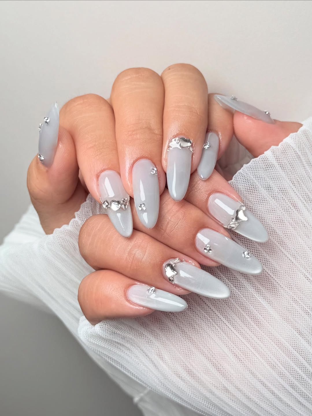 Unhas cinza com pedrarias e acabamento brilhante