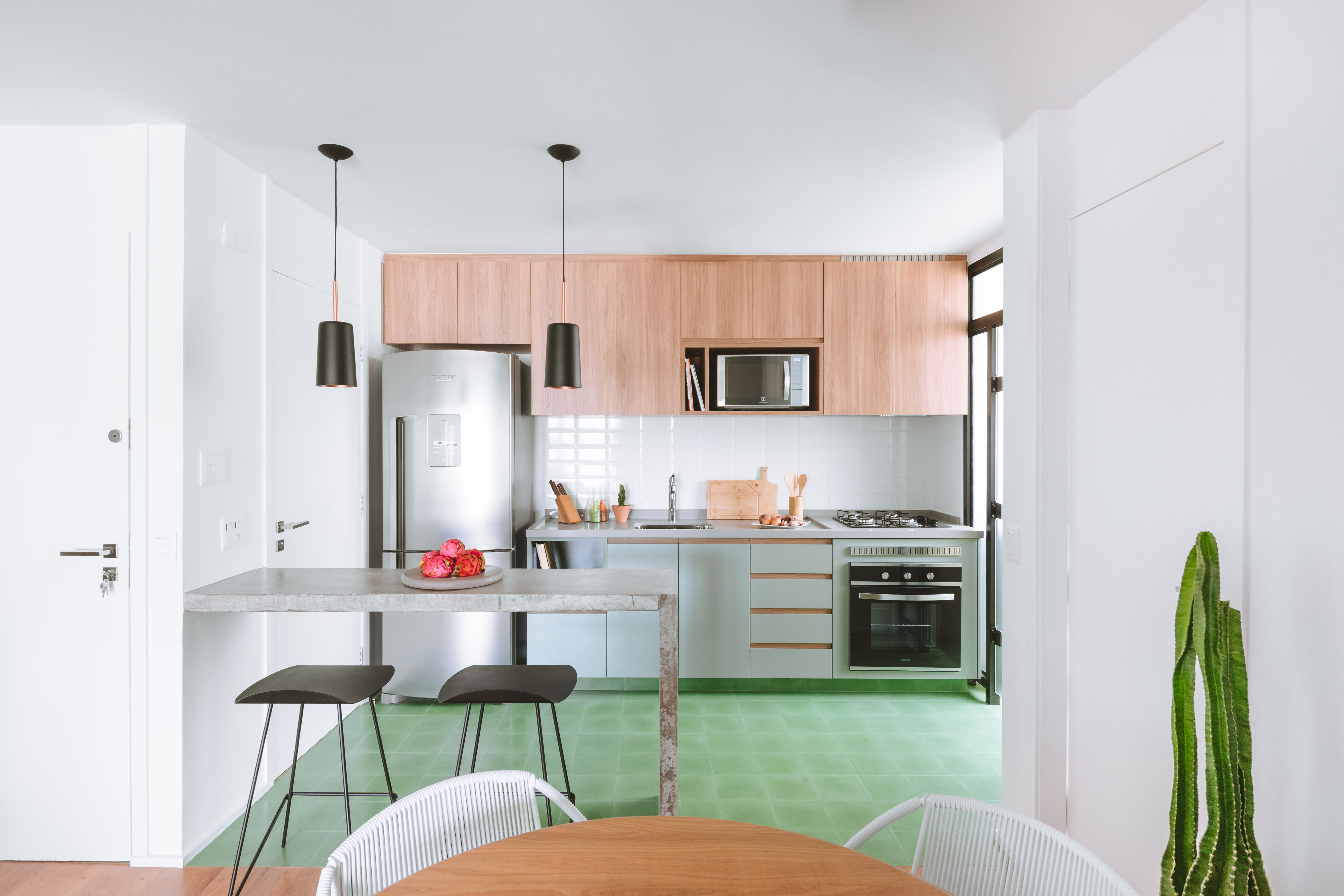 Cozinha pequena americana em piso verde e parede rosa.