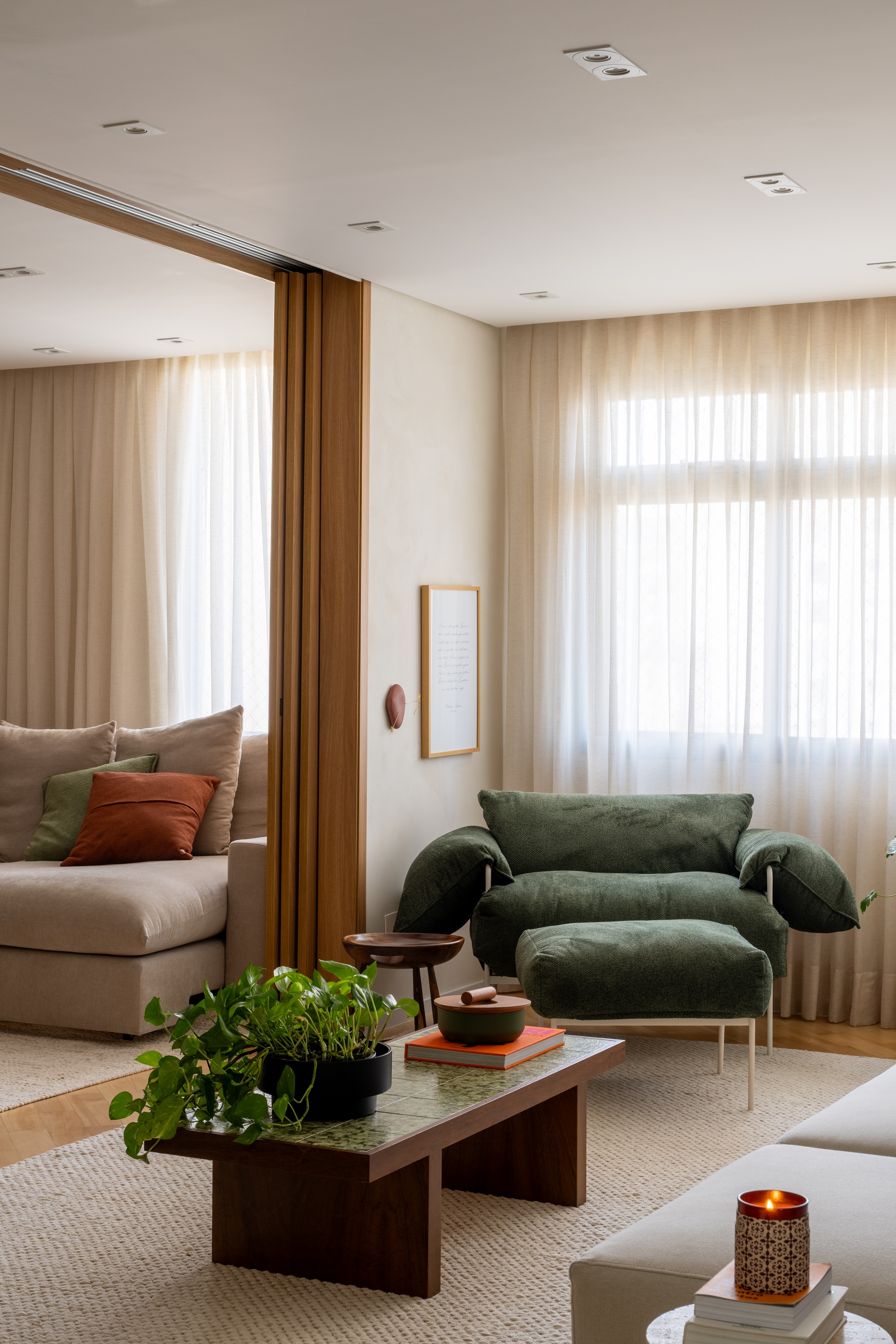 Sala de estar com paredes brancas, poltrona verde e mesa de centro com ladrilho hidr&aacute;ulico.