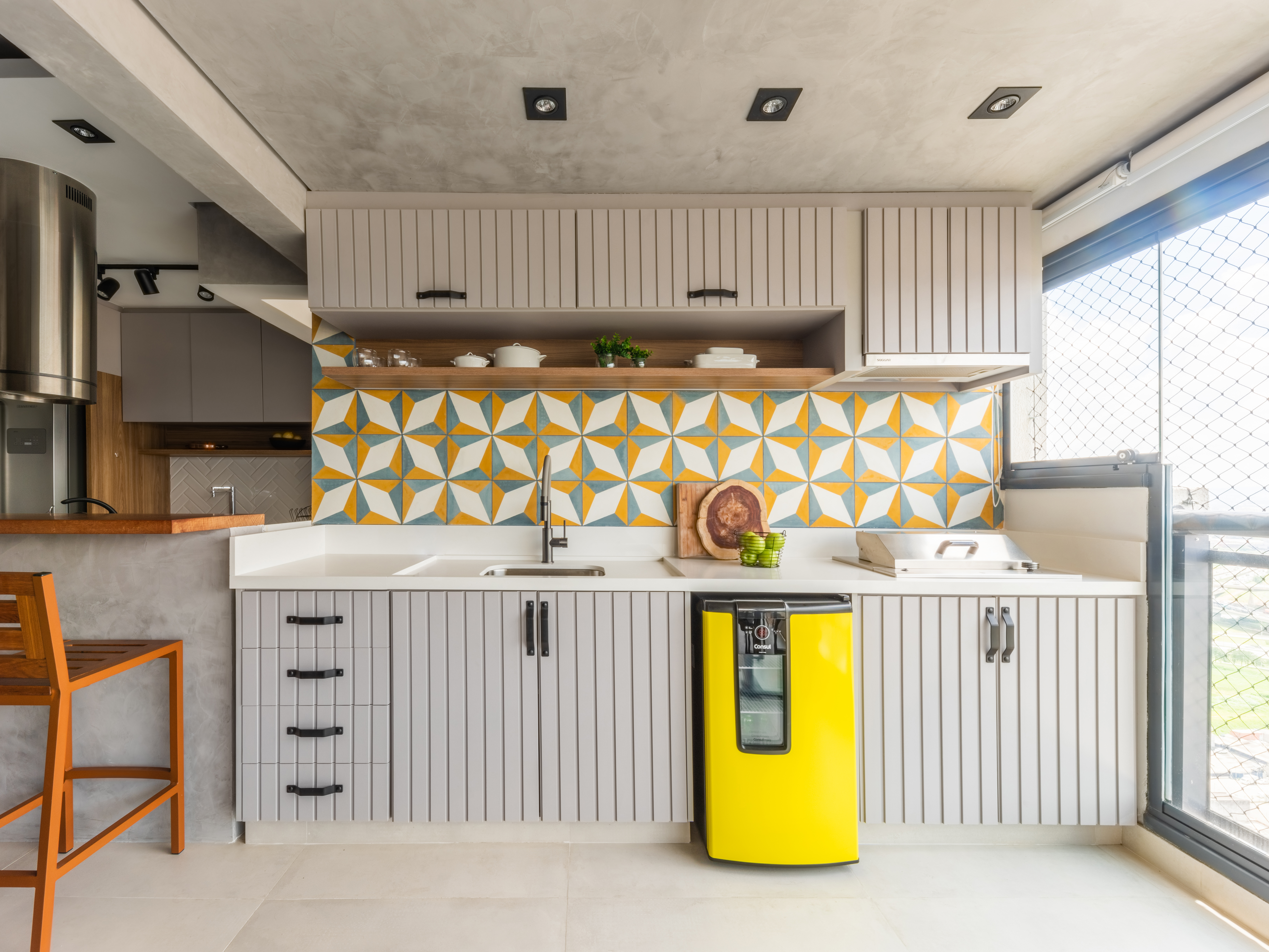 Cozinha com arm&aacute;rios em cinza claro, mini cooler amarelo e ladrilho hidr&aacute;ulico geom&eacute;trico