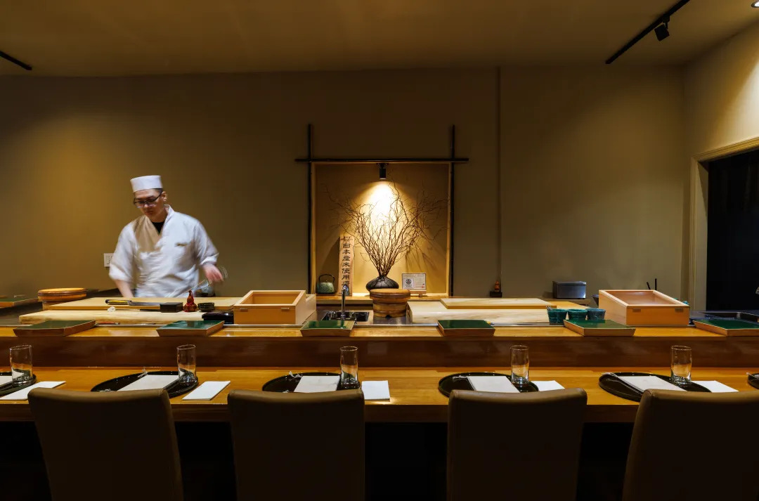 Restaurante estilo omakase com chef preparando a comida japonesa