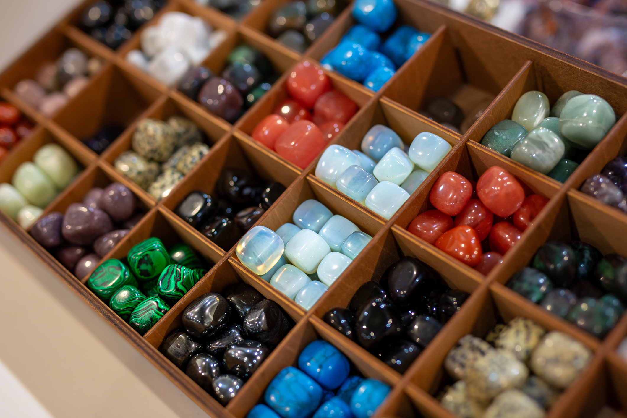 Vários cristais polidos organizados em divisórias, incluindo Quartzo Verde e outras pedras energéticas usadas para cura e equilíbrio espiritual em 2026.