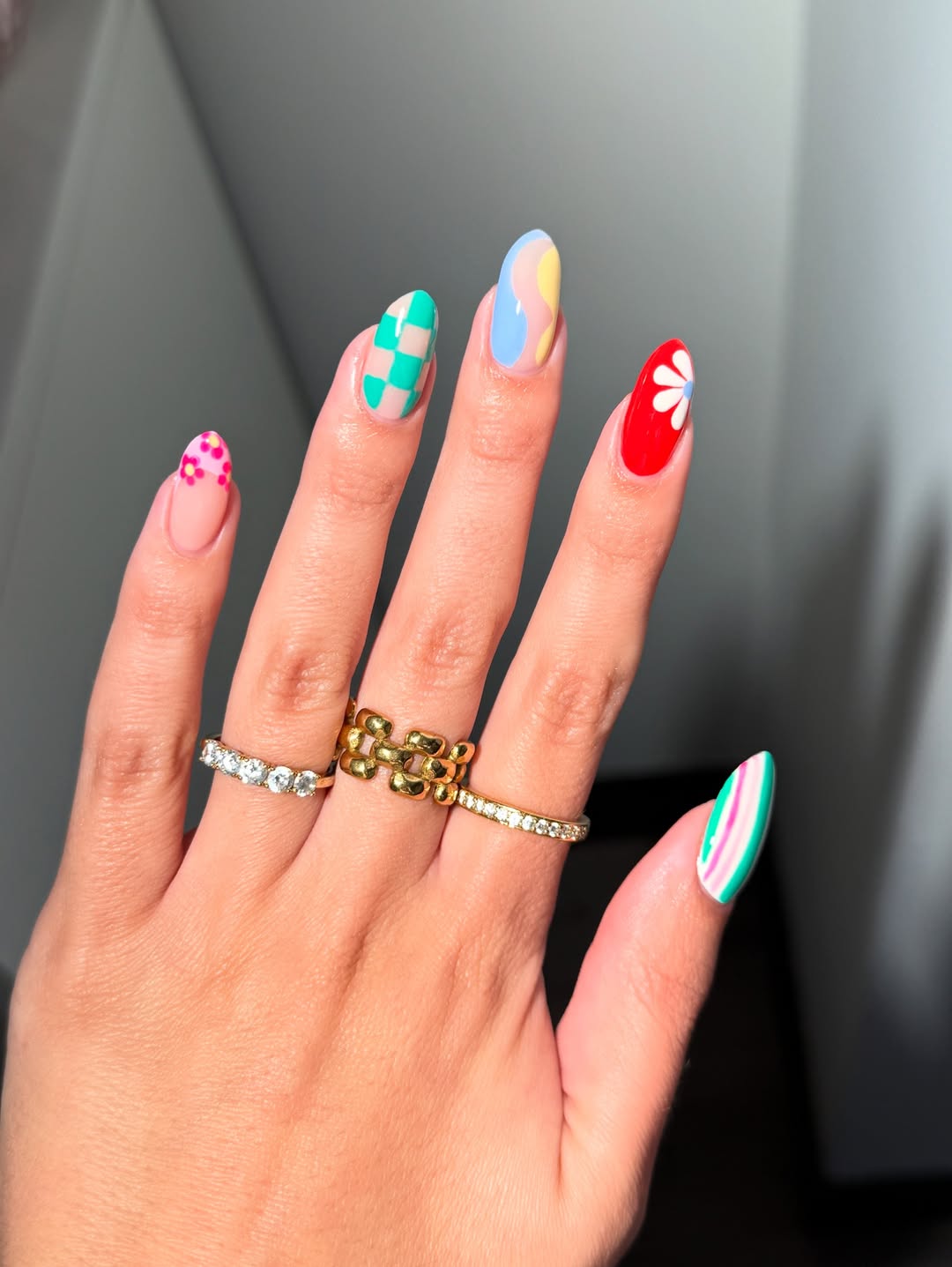 Foto de uma m&atilde;o com as unhas coloridas, com uma de cada cor