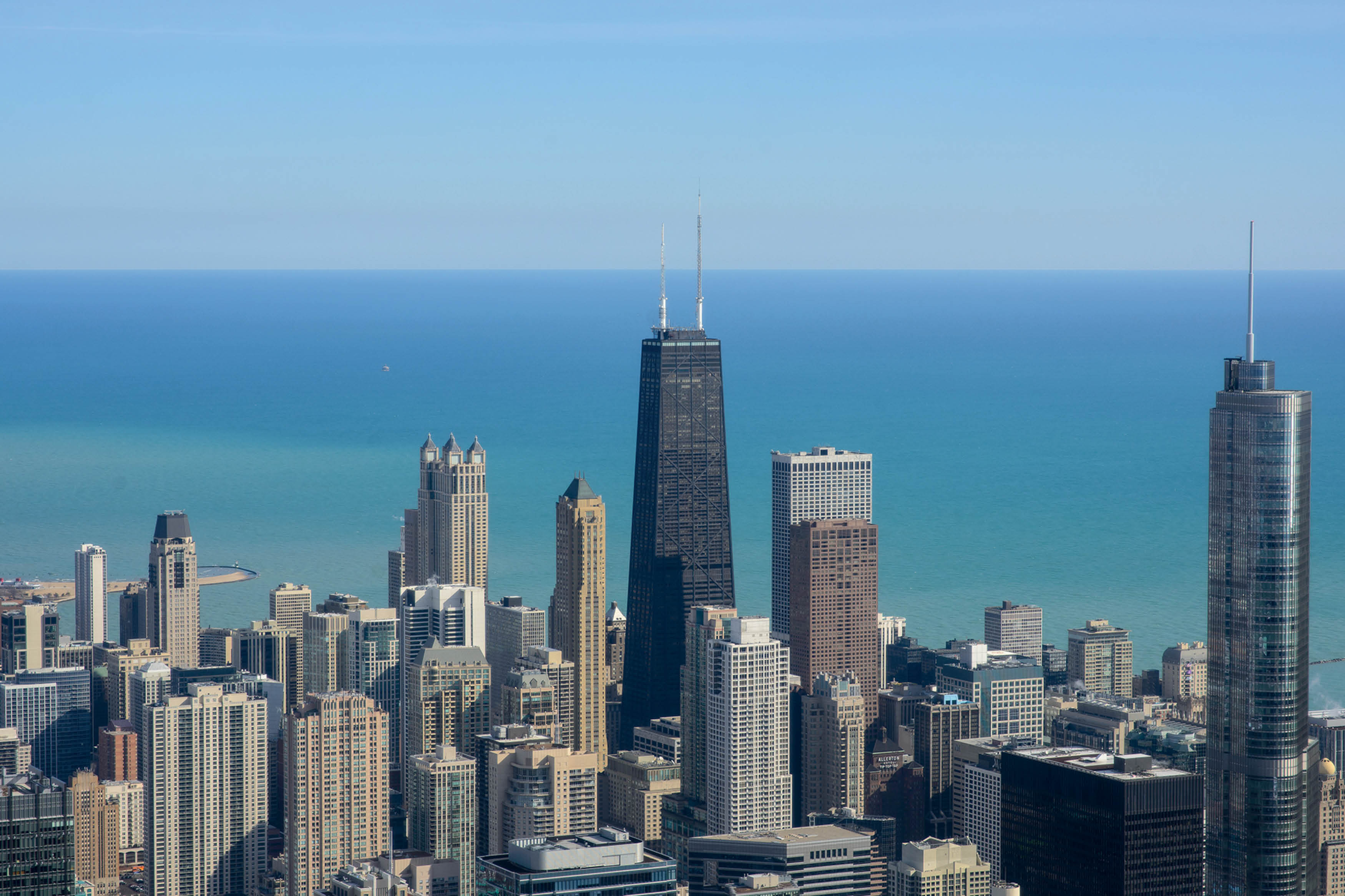 Vista panor&acirc;mica do skyline de Chicago com arranha-c&eacute;us e o Lago Michigan ao fundo, destacando a verticaliza&ccedil;&atilde;o e a arquitetura moderna da cidade