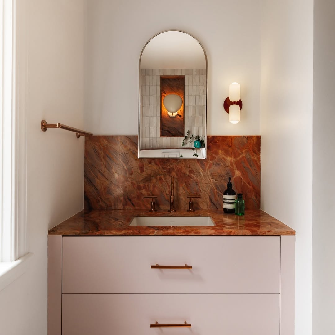 Banheiro infantil com m&aacute;rmore vermelho na bancada e arm&aacute;rio rosa beb&ecirc;
