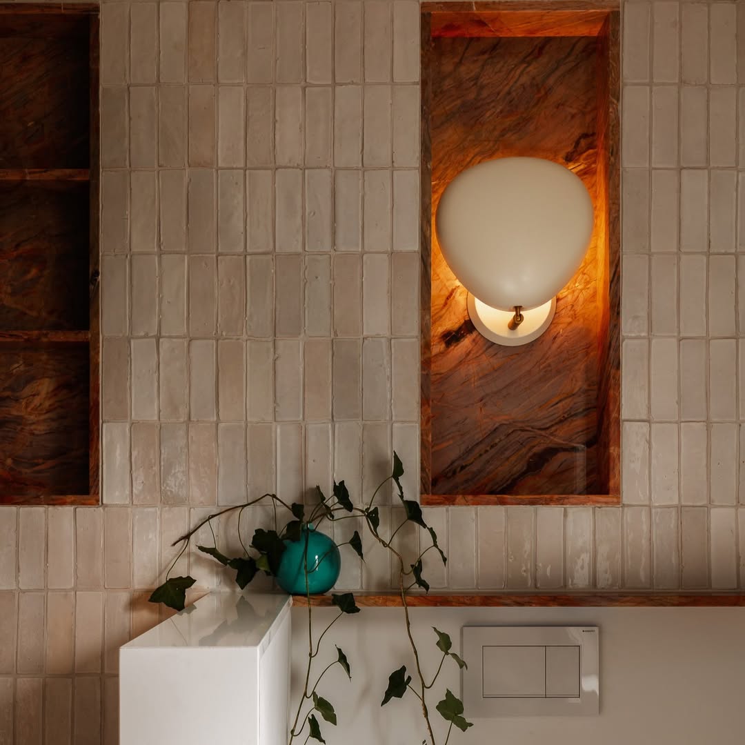 Banheiro com nichos para lumin&aacute;rias revestidos de m&aacute;rmore vermelho