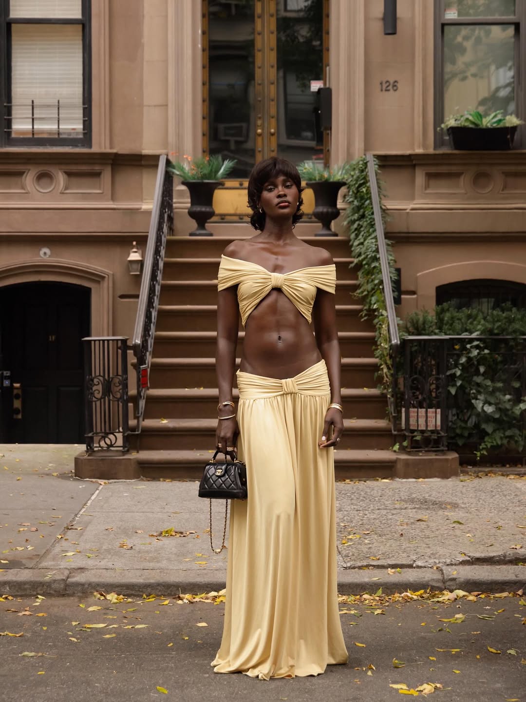 Foto de uma mulher negra usando um look composto por top e saia longa amarelos