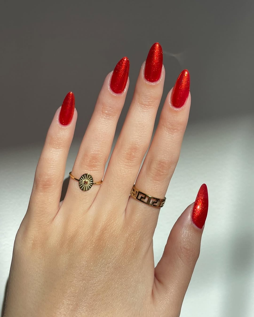 Foto de uma m&atilde;o com as unhas coloridas de vermelho cintilante