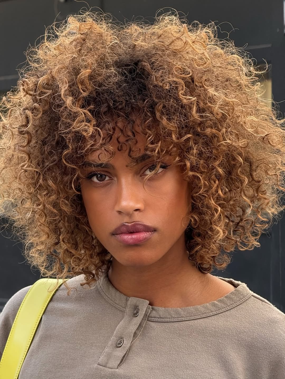 Foto de uma mulher negra com o cabelo cacheado cortado wolf cut