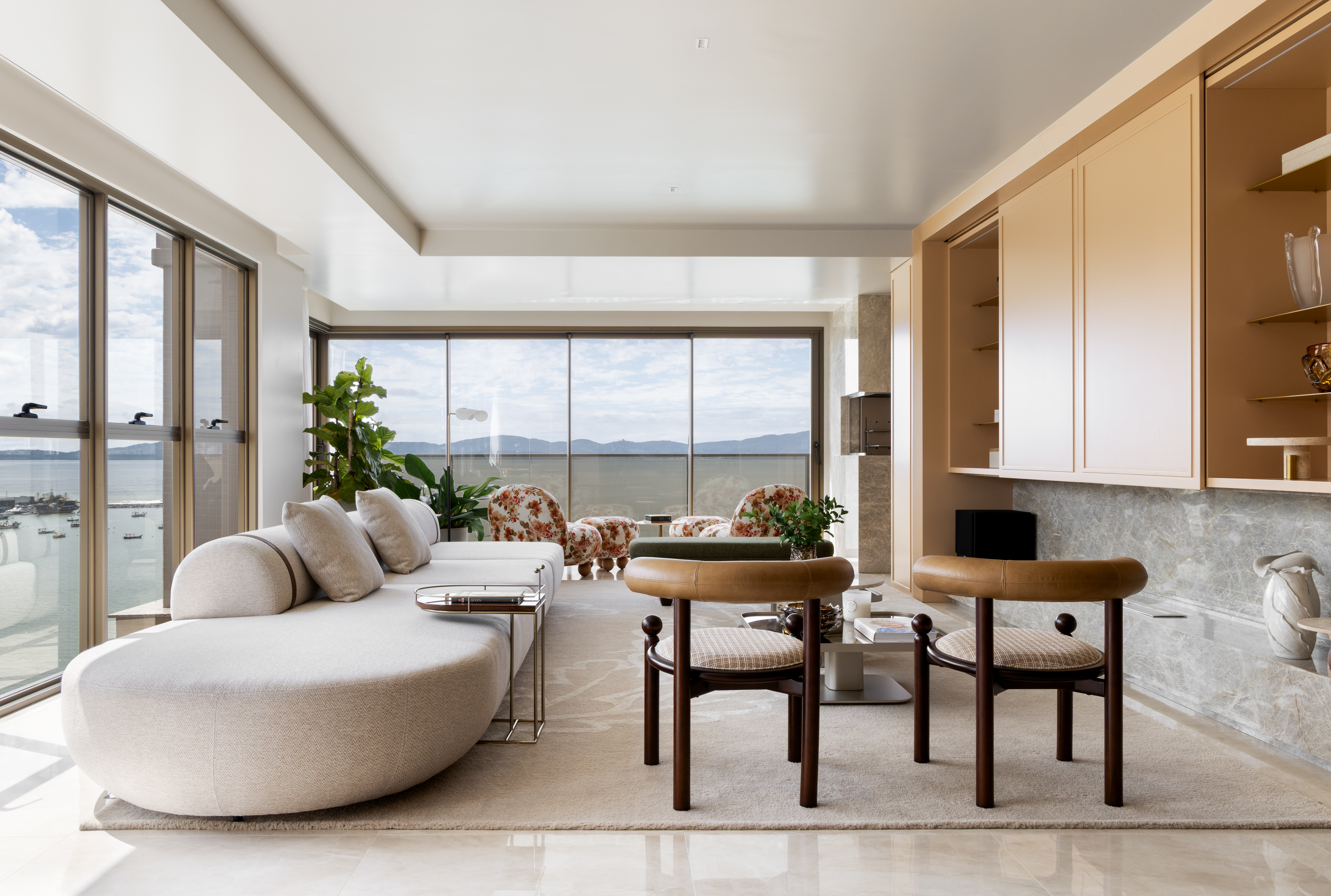 Salavde estar com mesa de centro, poltronas, sof&aacute; e janelas com vista para o mar