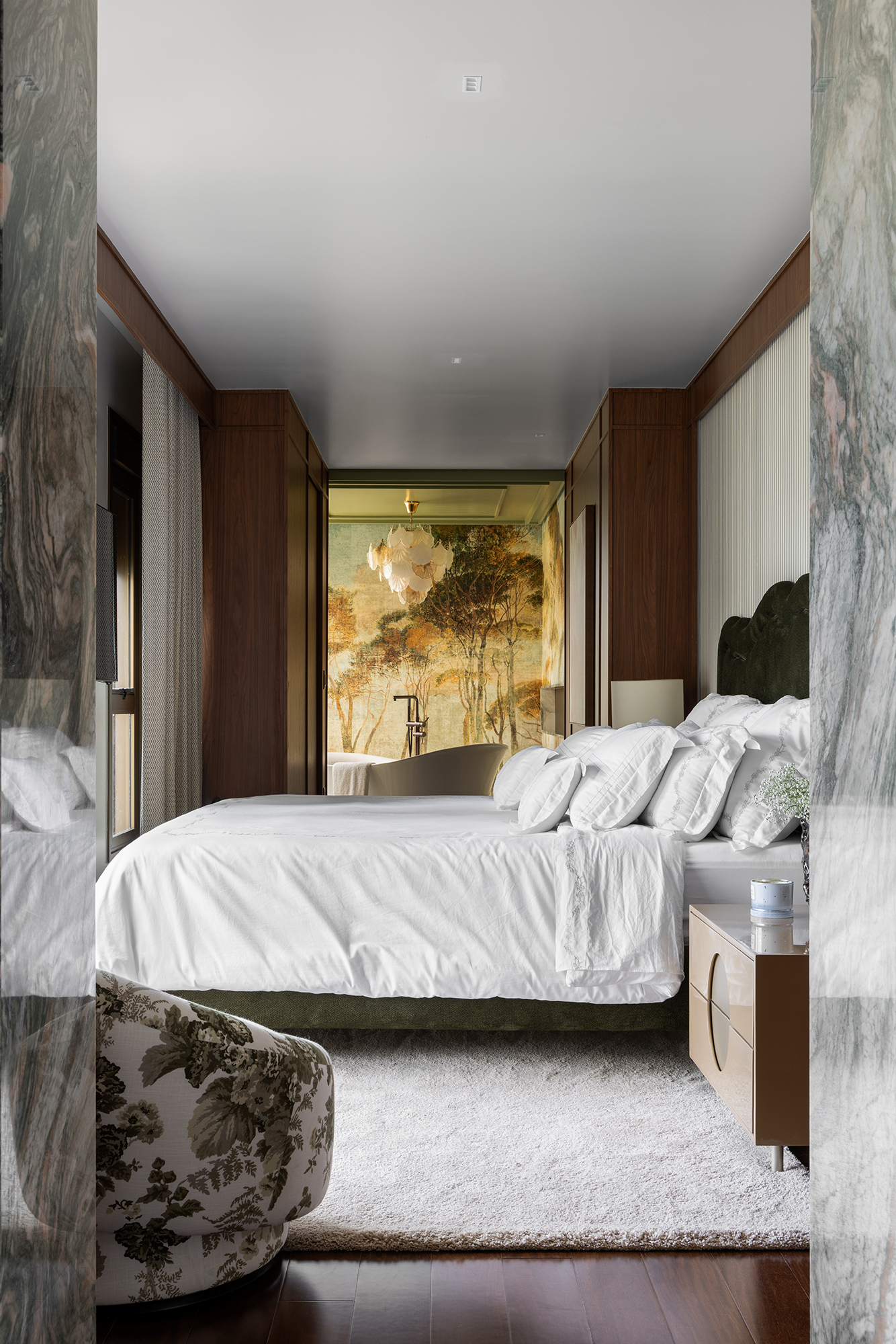 Su&iacute;te de casal com m&aacute;rmore verde, roupa de cama branca e banheiro com papel de parede em tons de amarelo e verde