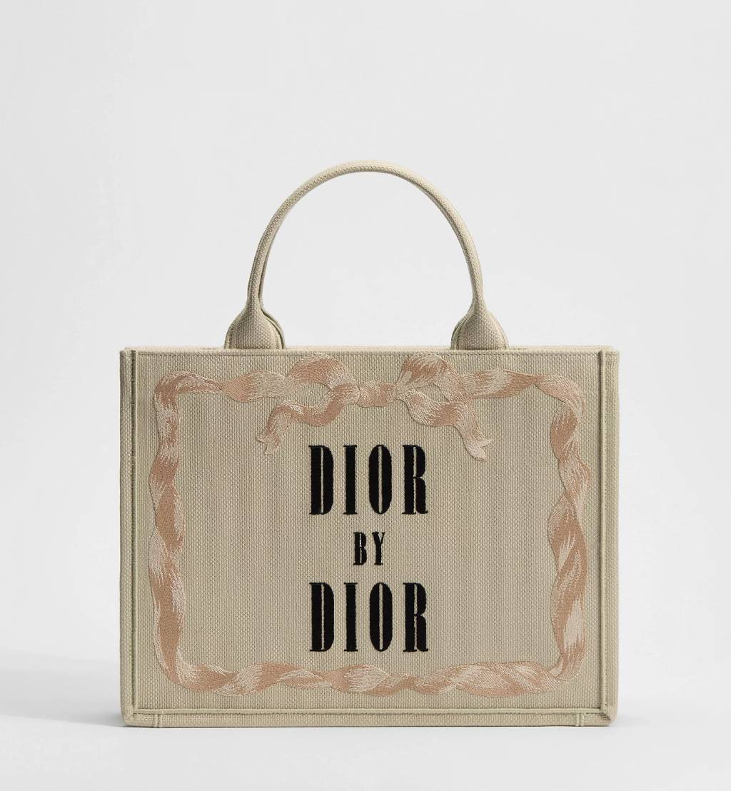 Bolsa Dior Book Tote em tecido bege com bordado &ldquo;Dior by Dior&rdquo;, inspirada na autobiografia de Christian Dior, modelo liter&aacute;rio criado por Jonathan Anderson para a cole&ccedil;&atilde;o que homenageia cl&aacute;ssicos da literatura