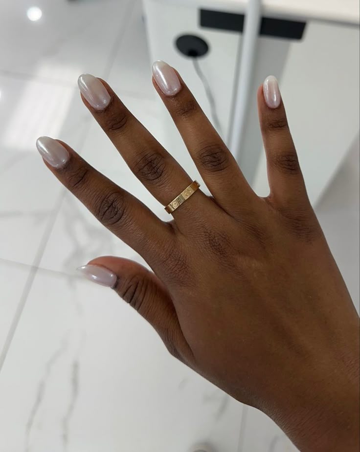 Esmalte perolado claro em unhas amendoadas valorizando a pele negra