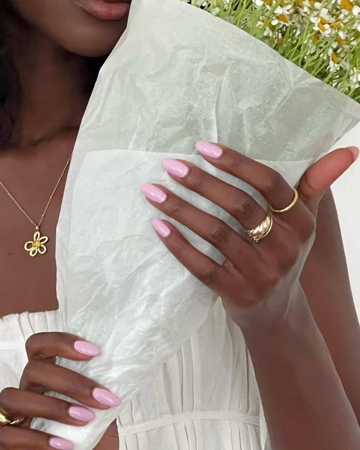 Esmalte rosa claro em unhas amendoadas real&ccedil;ando a pele negra