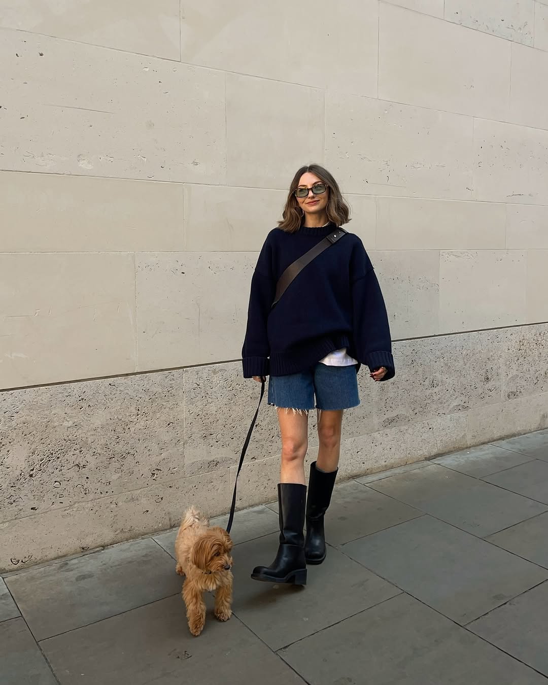 Tric&ocirc; oversized com bermuda jeans e bota de cano alto preta alonga a silhueta com contraste