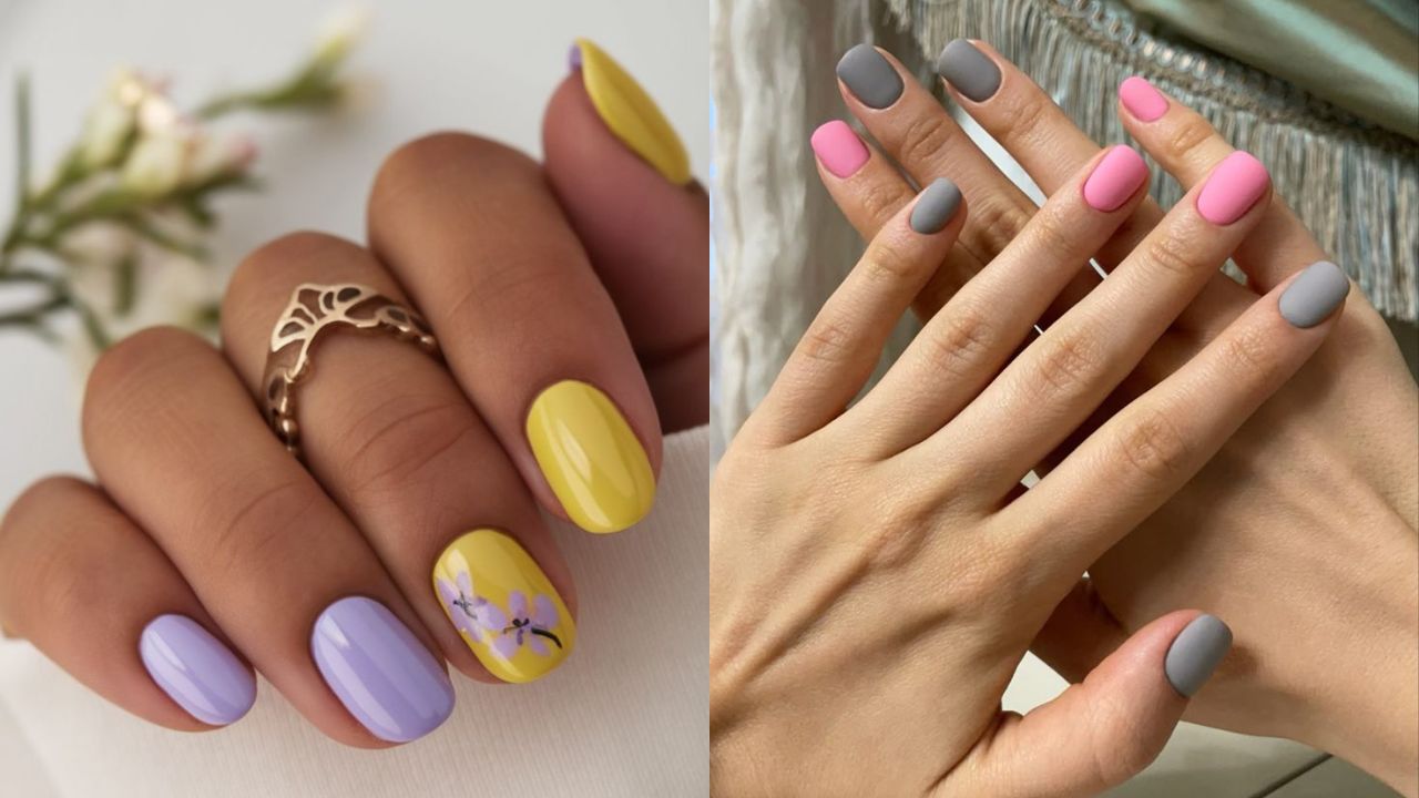 Unhas em tons suaves, com destaque para amarelo e lil&aacute;s e uma delicada nail art floral em um dos dedos. Ao lado, m&atilde;os com esmalta&ccedil;&atilde;o minimalista em rosa e cinza, mostrando a tend&ecirc;ncia de alternar cores entre os dedos.