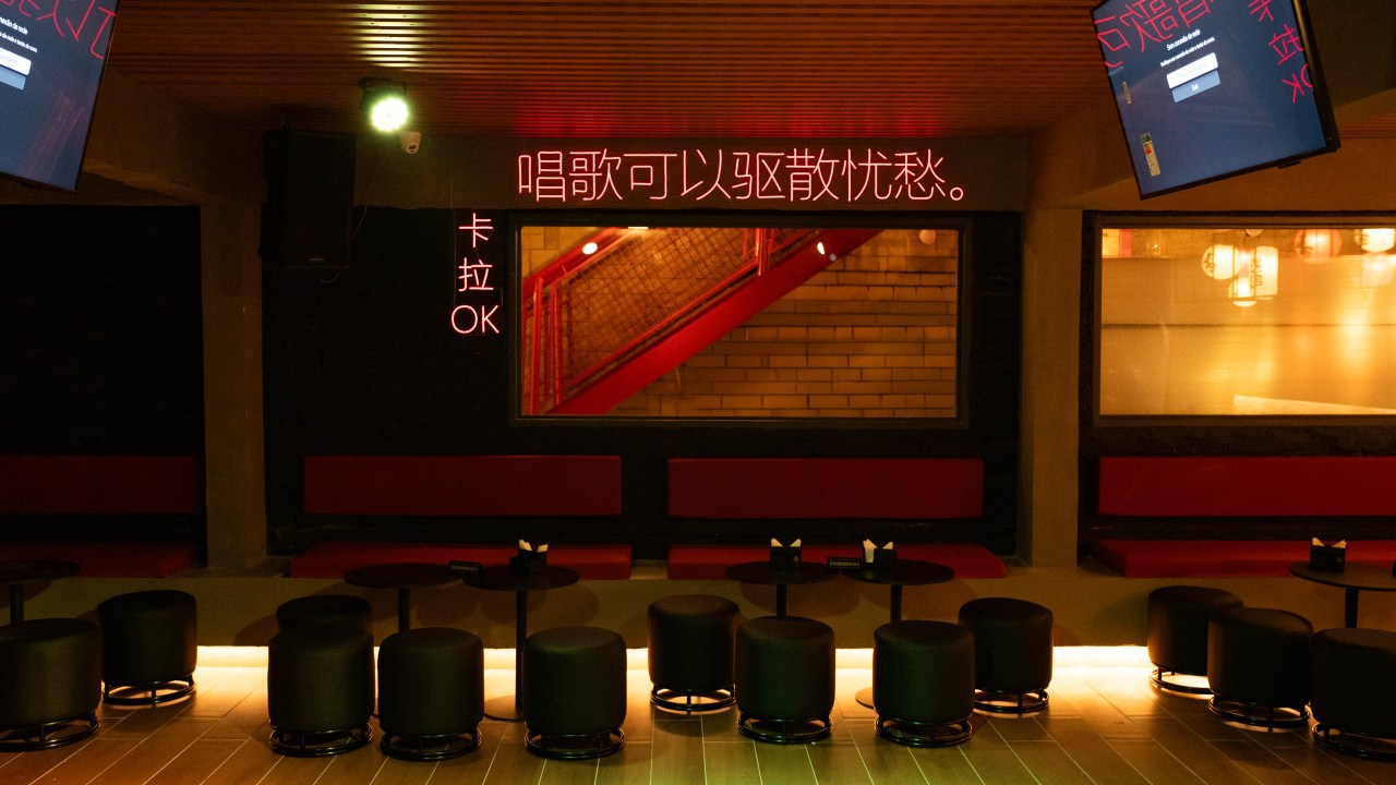 Interior da nova unidade do Yellow K em Pinheiros, São Paulo, com iluminação em neon, mesas e lounge, inspirado em bares asiáticos e espaço de karaokê.