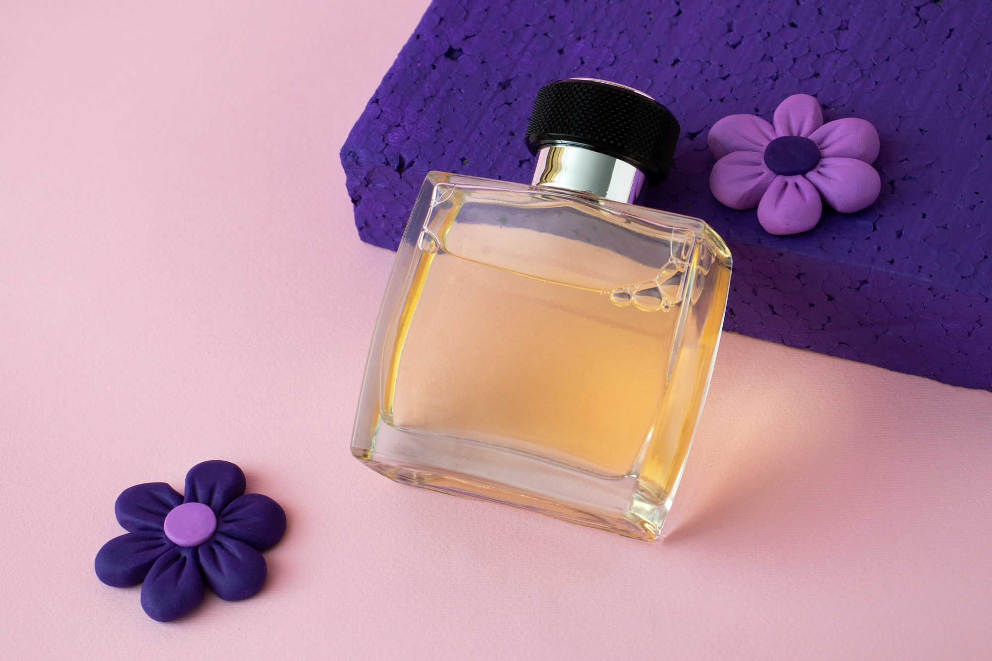 Imagem de frasco de perfume transparente em fundo rosado, referenciando a mat&eacute;ria de perfumes que afetam a tireoide