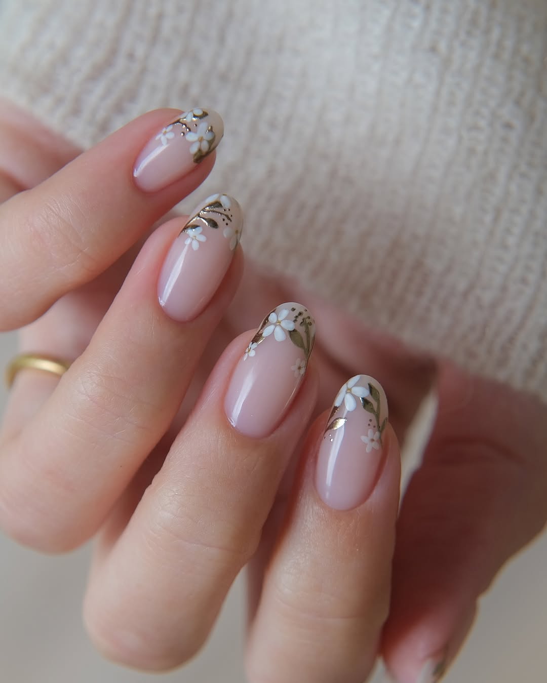 Close em m&atilde;os femininas usando esmalta&ccedil;&atilde;o com nail art floral branca e verde