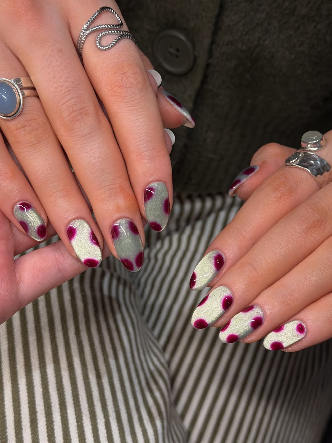 Unhas olhos de gato estampadas em verde com manchas vinho