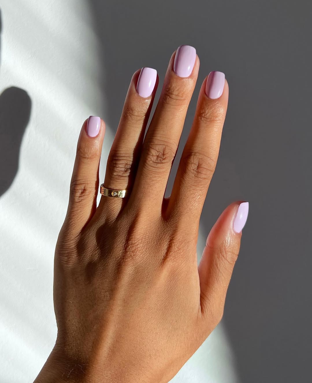 Foto de uma m&atilde;o com unhas coloridas de rosa
