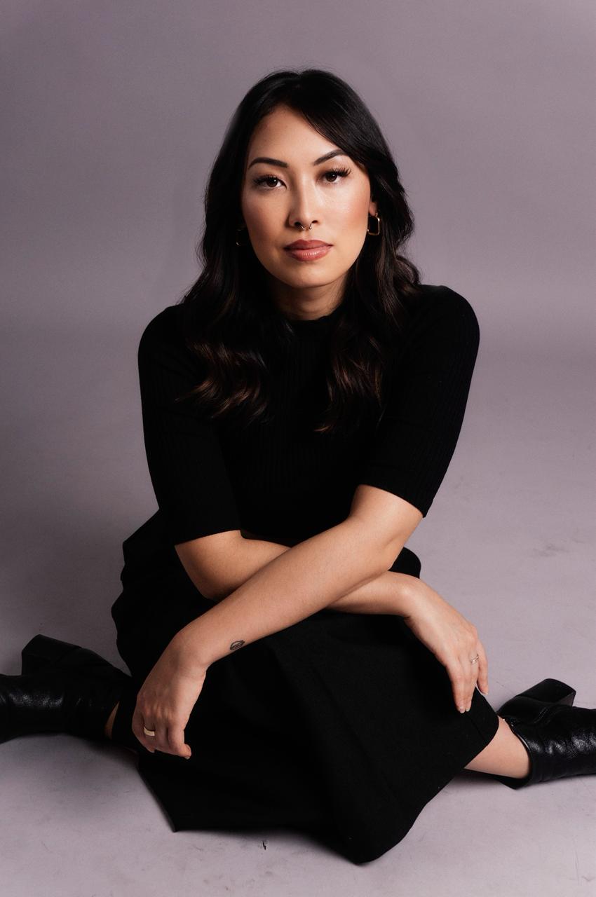 Foto da atriz Ana Hikari vista de frente, sentada e de bra&ccedil;os cruzados