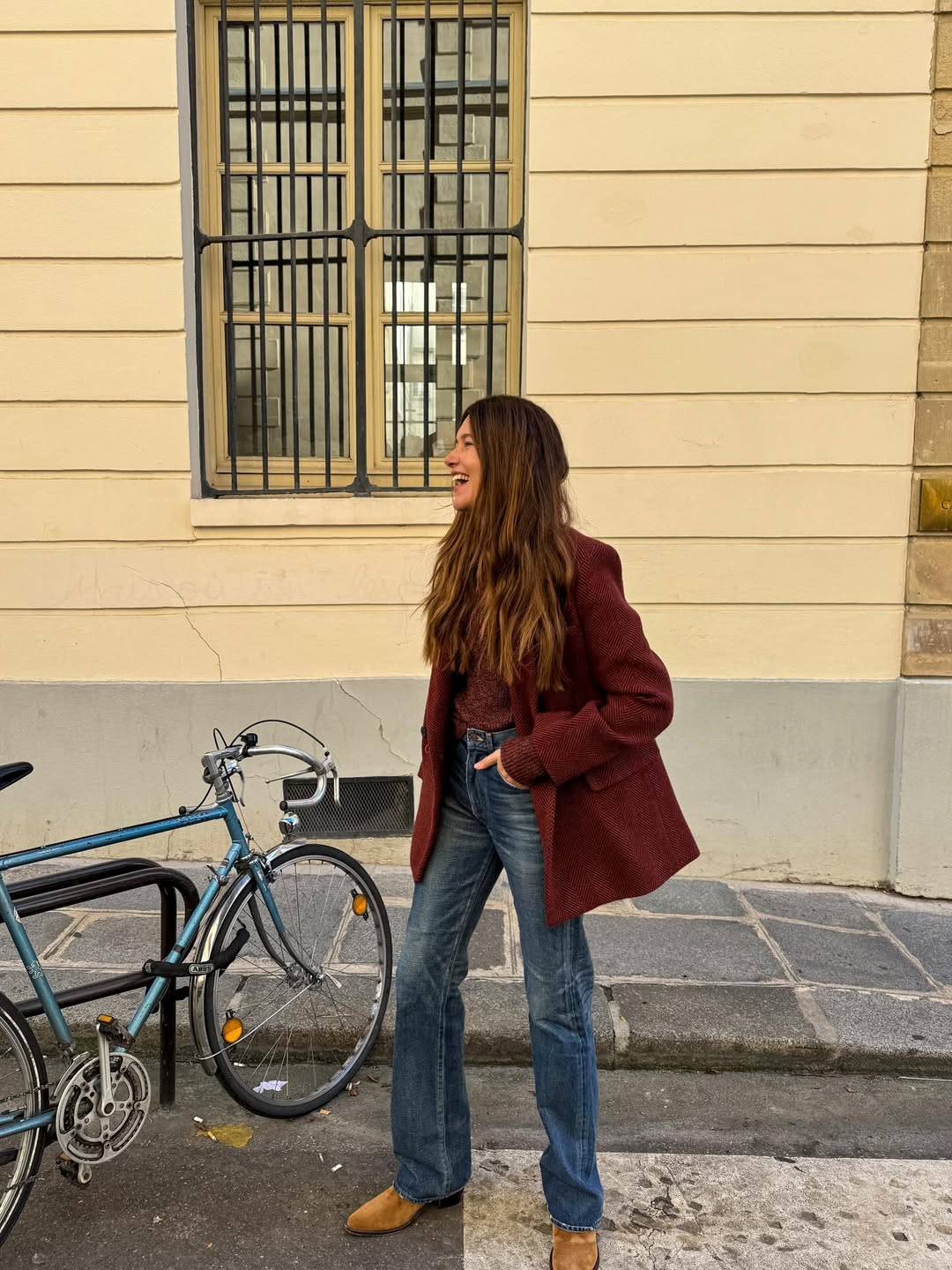 Foto de uma mulher usando um look composto por blazer vinho, cal&ccedil;a boot cut e sapatilha