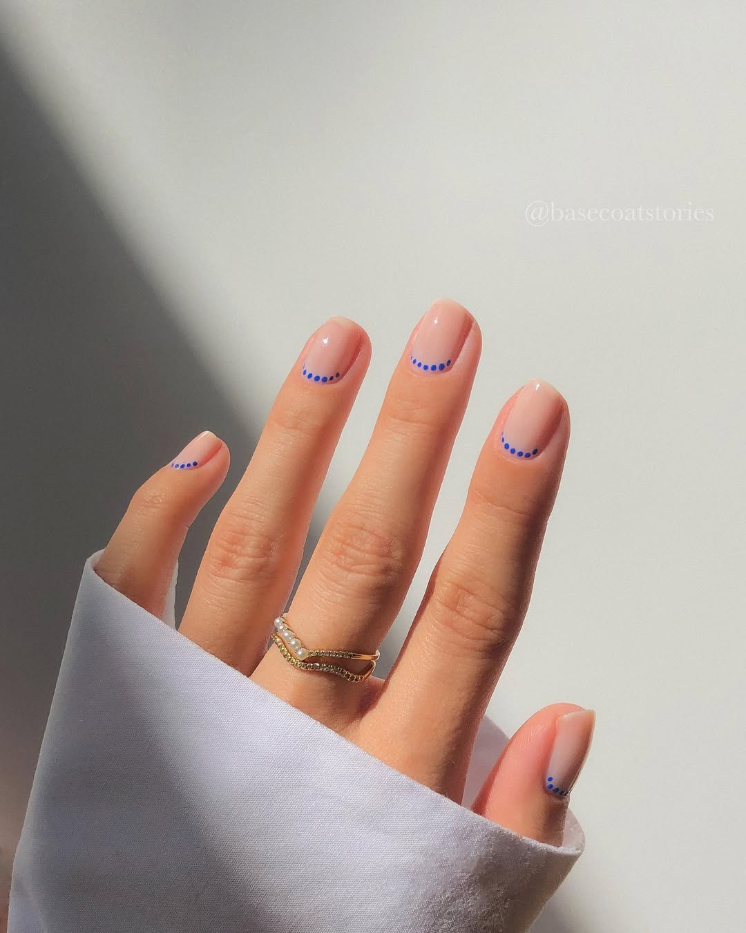 Nail art minimalista com pontinhos azuis sobre base natural nas unhas