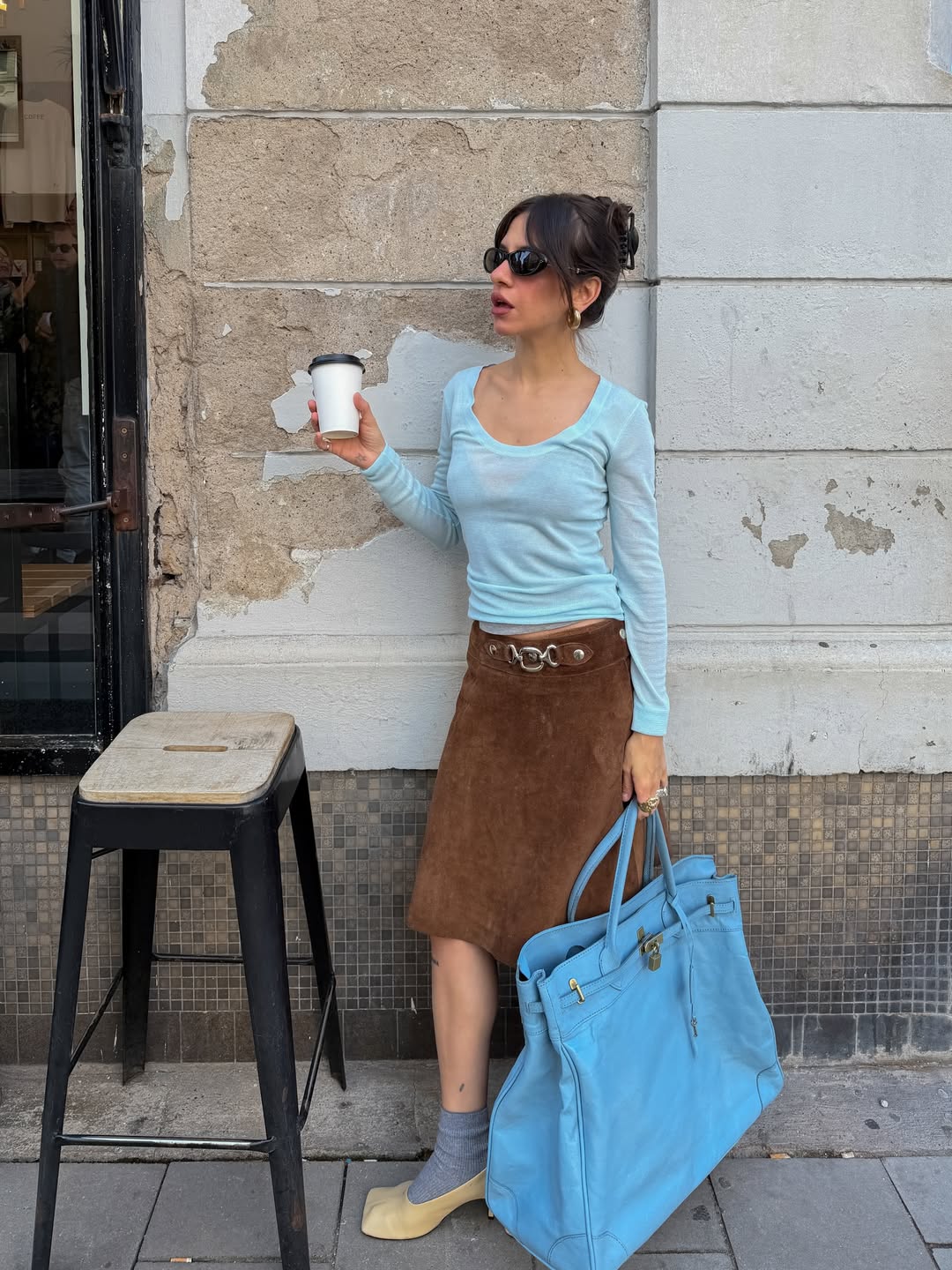 Look com blusa azul Bridgerton combinada com saia marrom e bolsa no mesmo tom suave