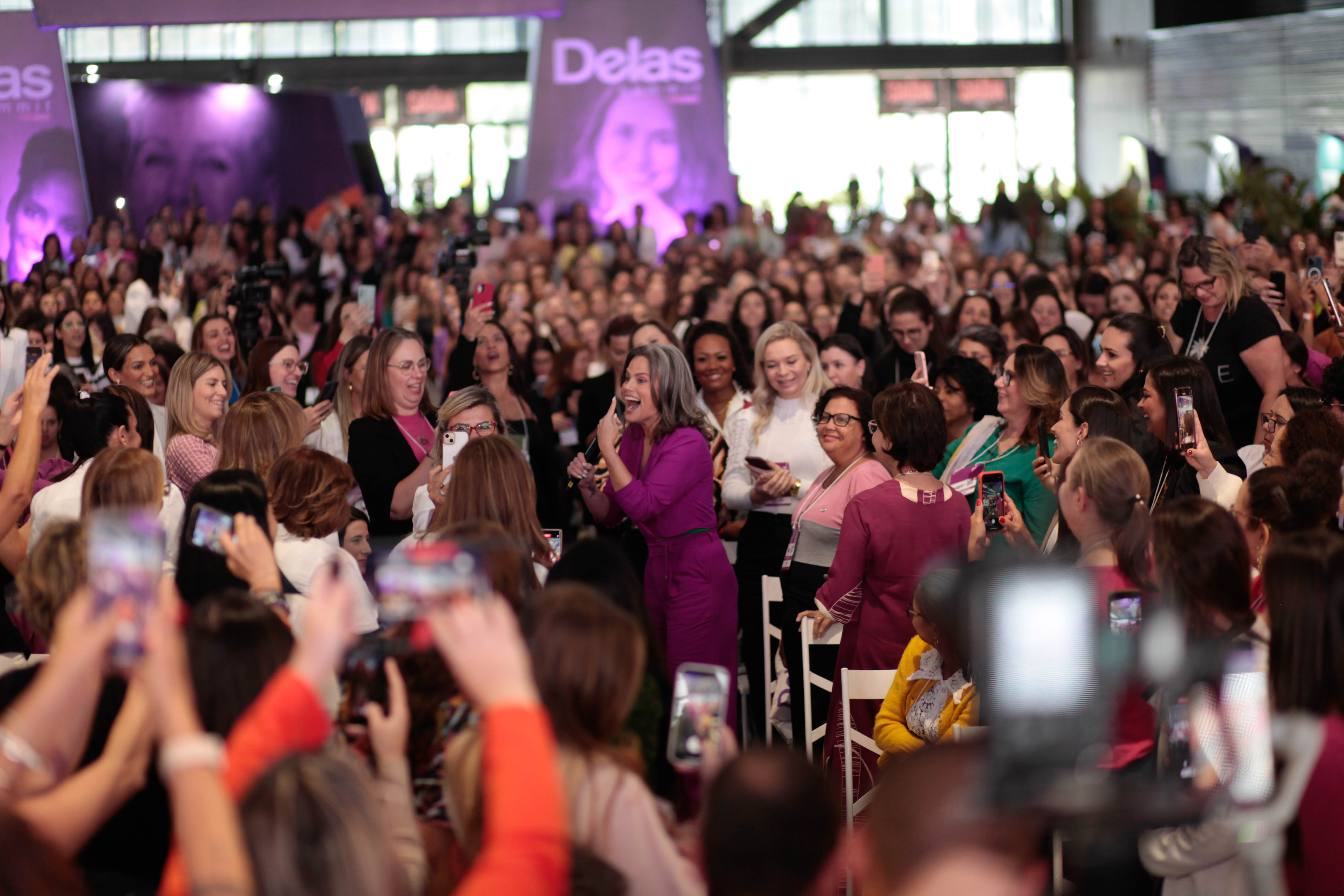 Maria C&acirc;ndida caminha entre o p&uacute;blico durante o Menopausa Summit, cercada por mulheres que registram o momento em um evento dedicado &agrave; sa&uacute;de feminina