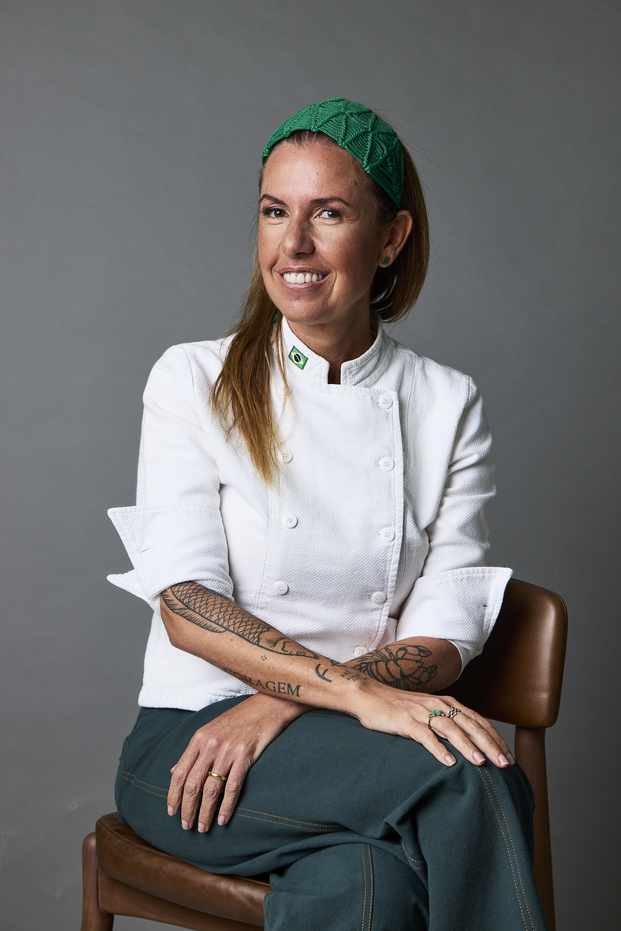 Retrato da chef Morena Leite de d&oacute;lm&atilde; branca e sentada num banco de madeira