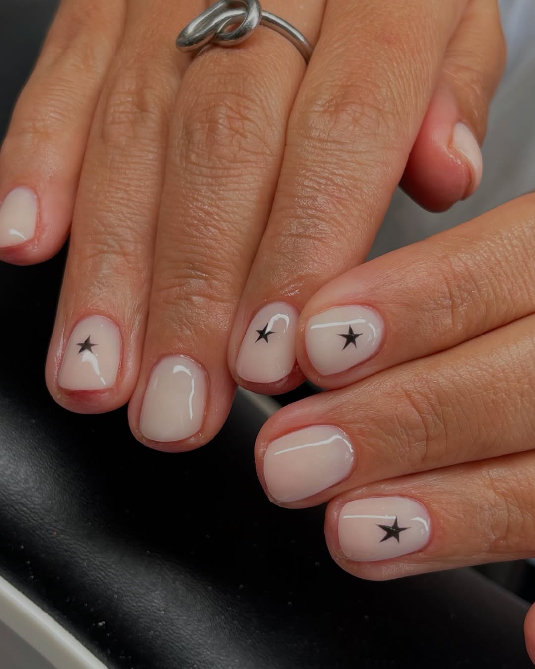 Unhas brancas decoradas com pequenas estrelas pretas minimalistas