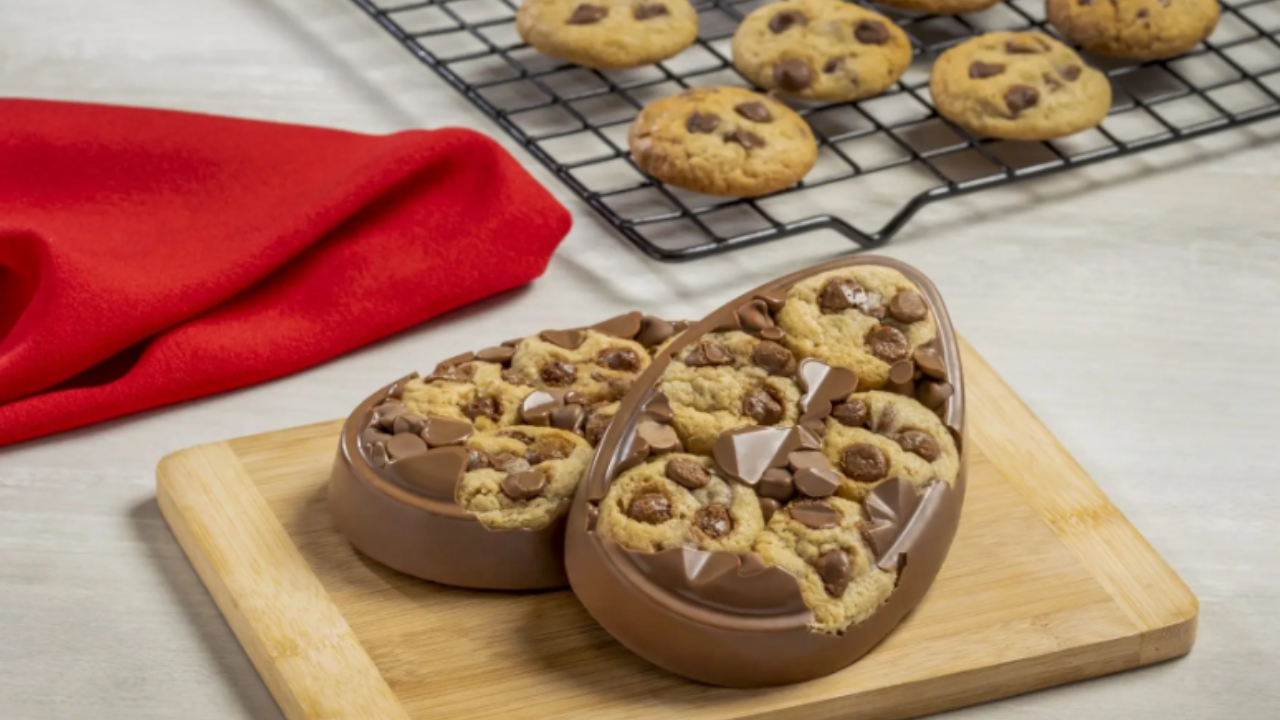 Ovo de Páscoa plano de cookies servido numa tábia de madeira ao lado de assadeira de cookies