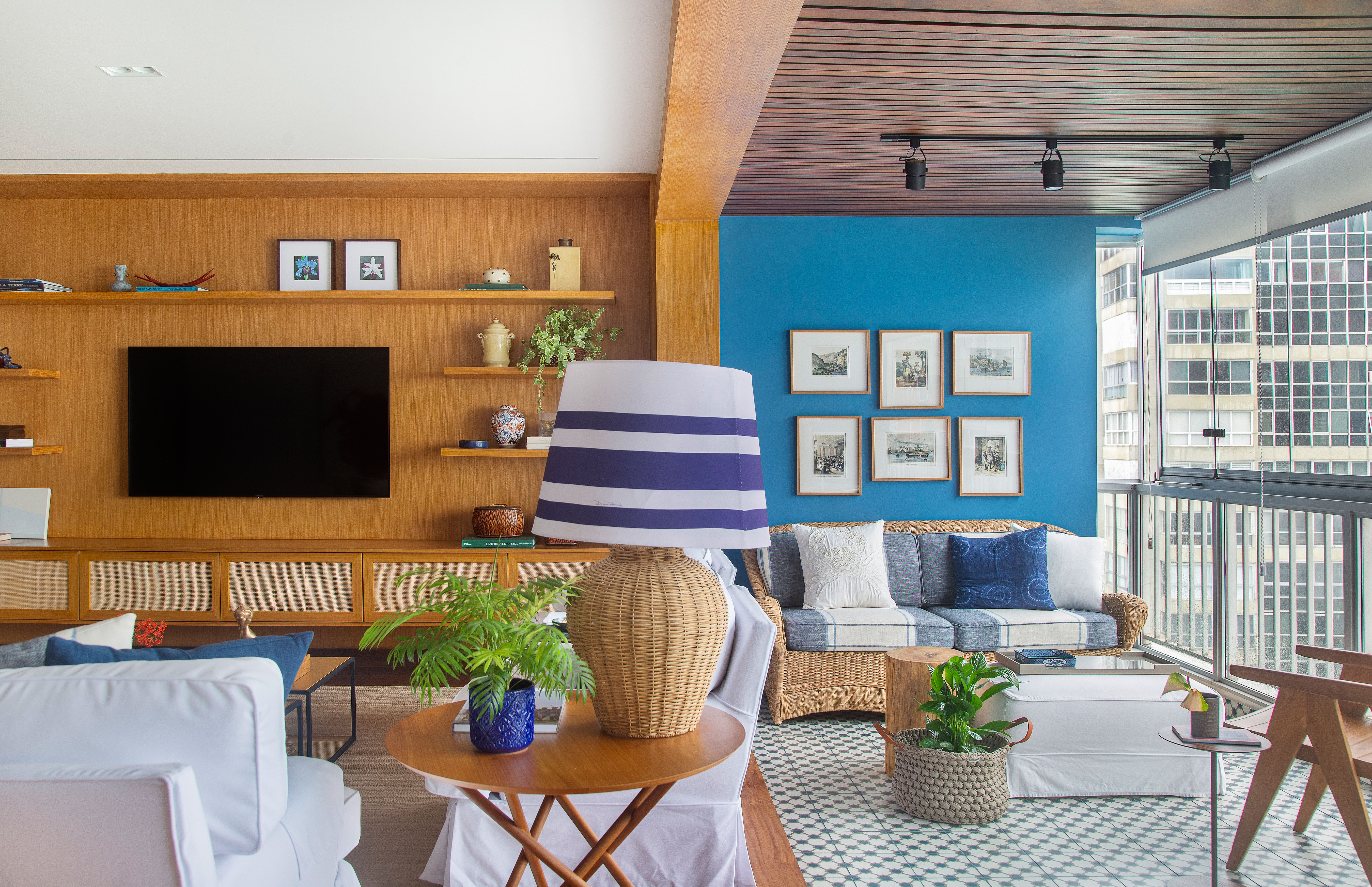 Sala de estar e varanda integradas em apartamento com paredes em madeira e azul