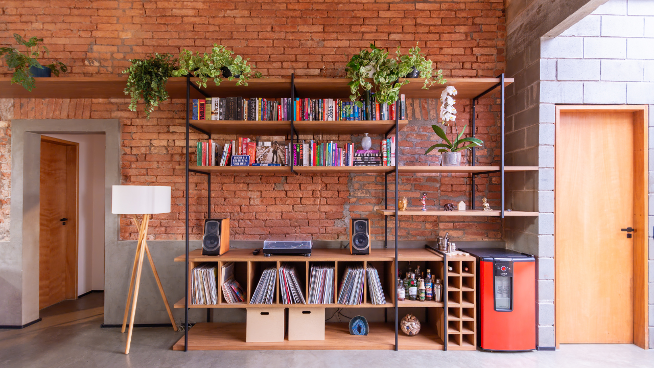 Parede de tijolinhos em sala de estar com estante de livros à frente