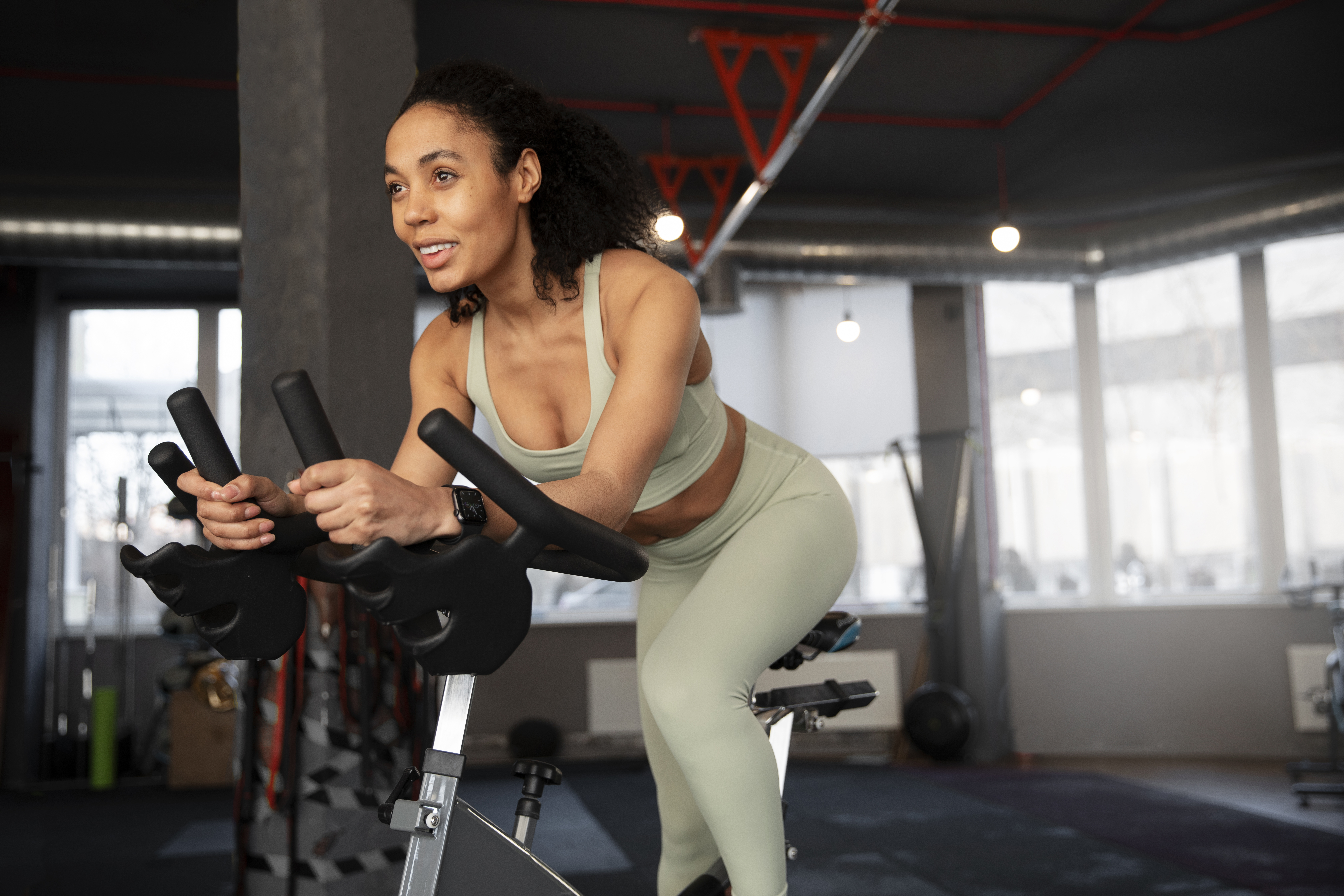 Mulher usando look verde de academia fazendo exerc&iacute;cio de spinning