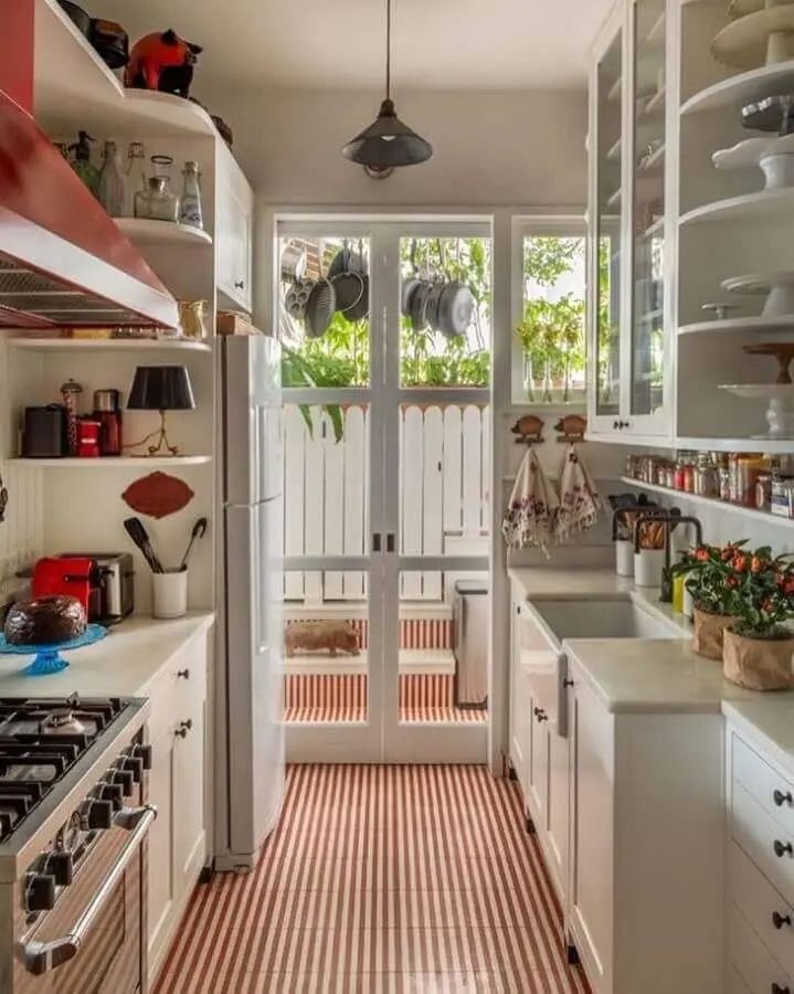 Cozinha com piso vermelho e arm&aacute;rios brancos franceses