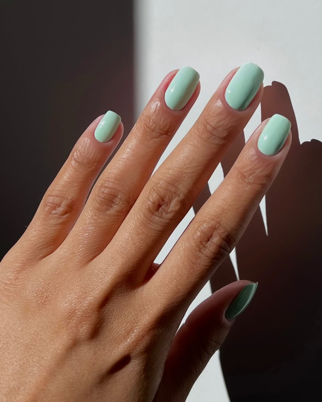 Foto de uma m&atilde;o com as unhas coloridas de turquesa
