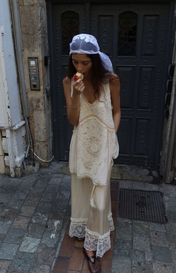 Foto de uma mulher usando um look composto por headpiece e roupas de seda com bordados e renda