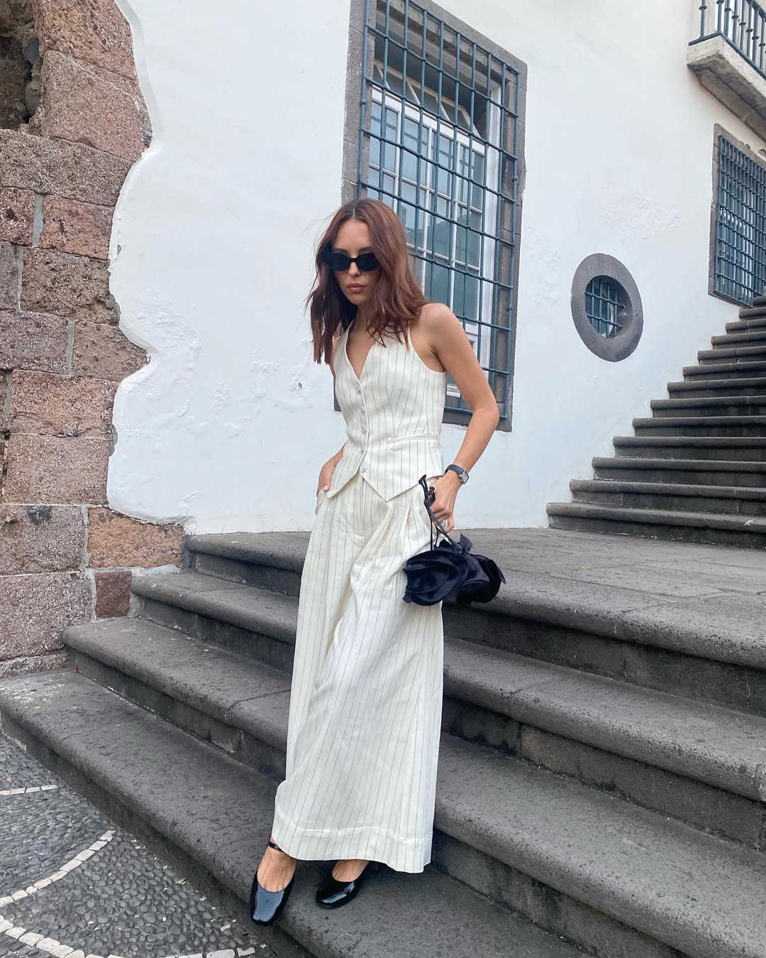 Foto de uma mulher usando um conjunto de alfaiataria branco com estampa risca de giz